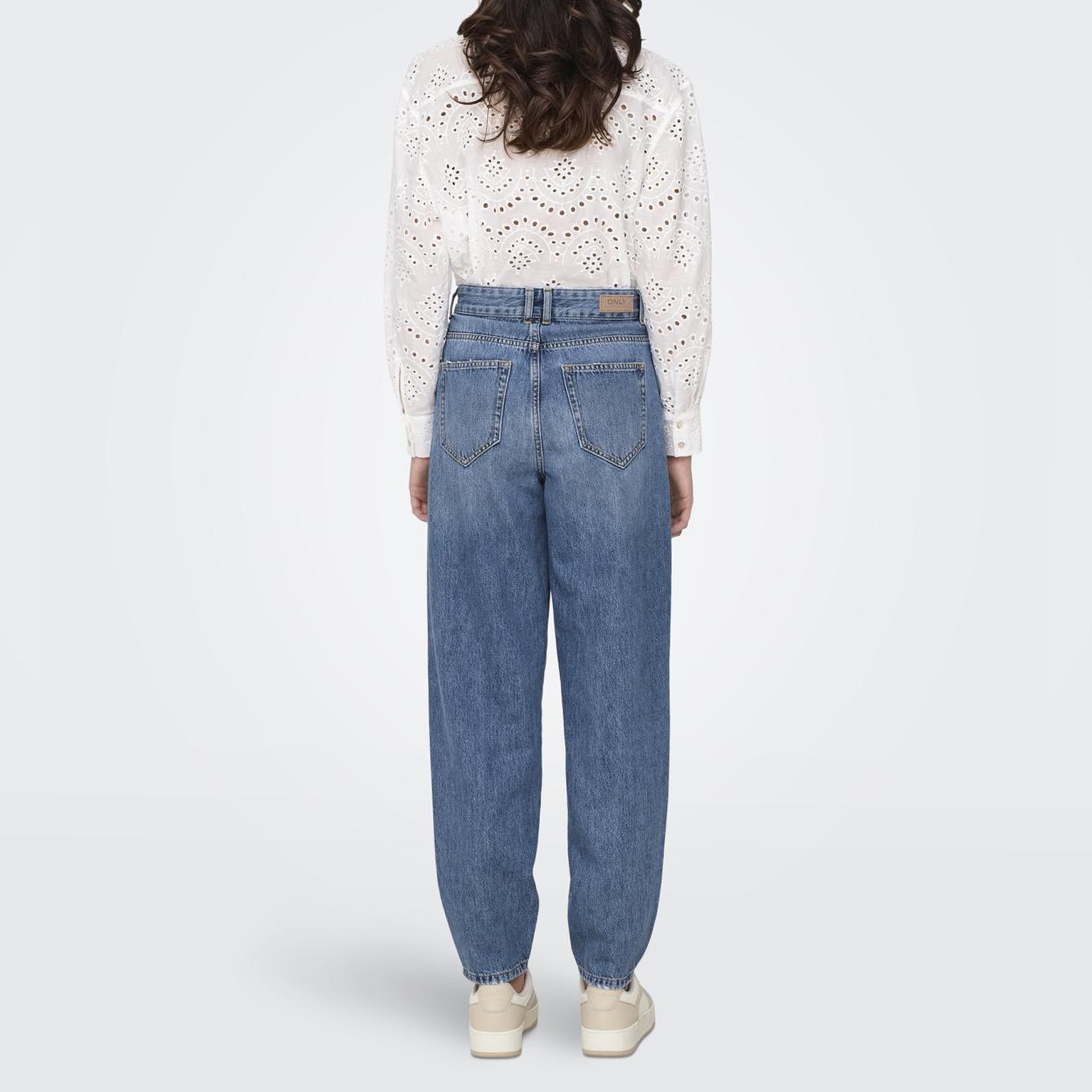 Calças de ganga azuis largas vistas de trás com camisa branca e sapatos claros