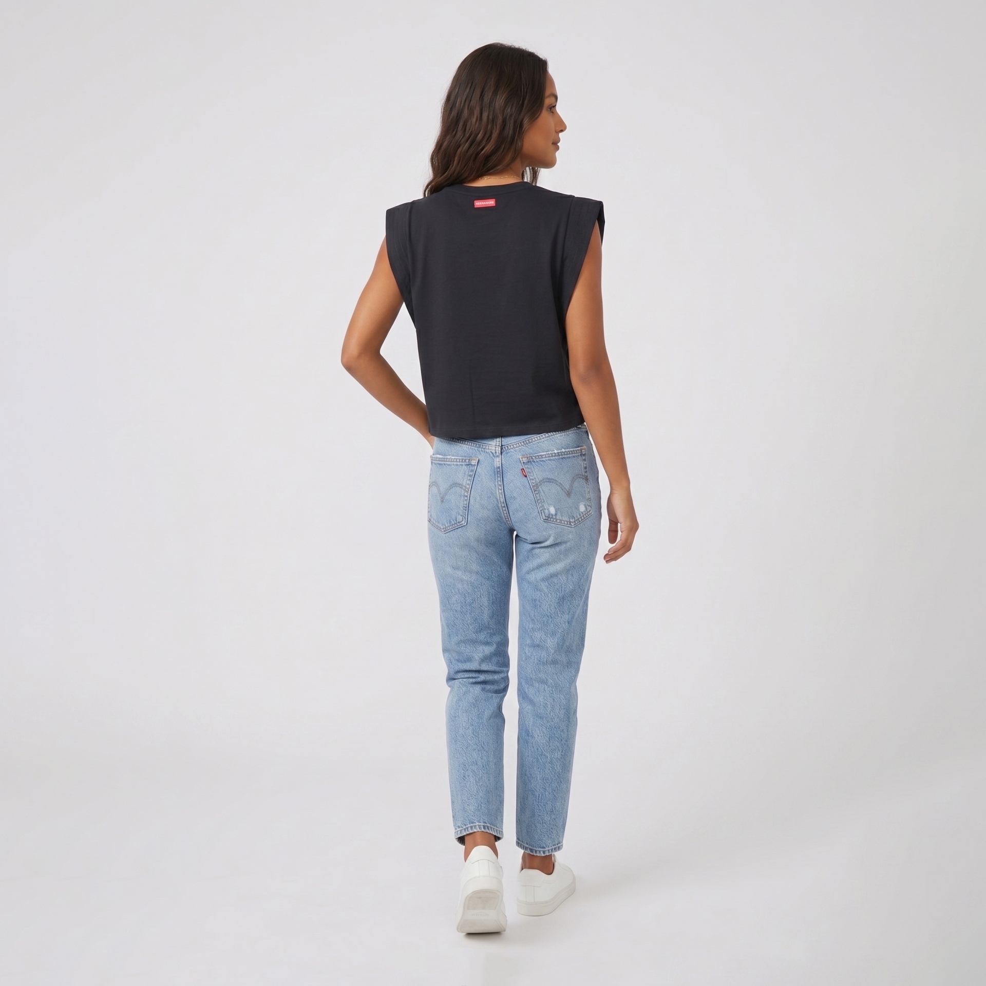 Mulher com camisola preta e calças de ganga vistas de costas