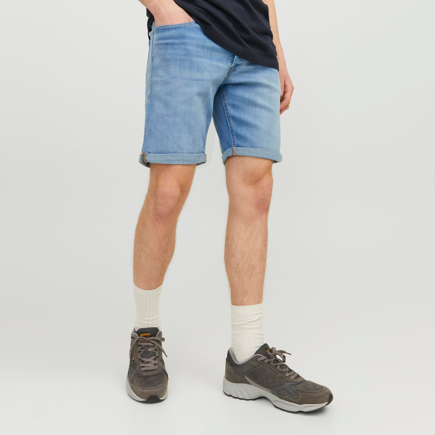 Calções de ganga azul claro com bainha dobrada e sapatilhas cinzentas