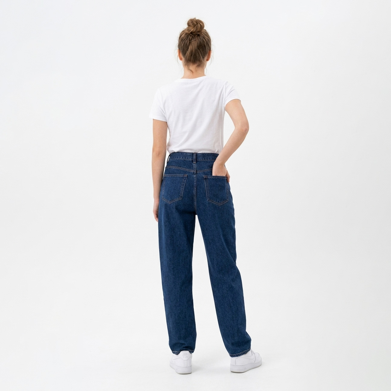 Mulher de costas com t-shirt branca, jeans azul escuro e sapatilhas brancas