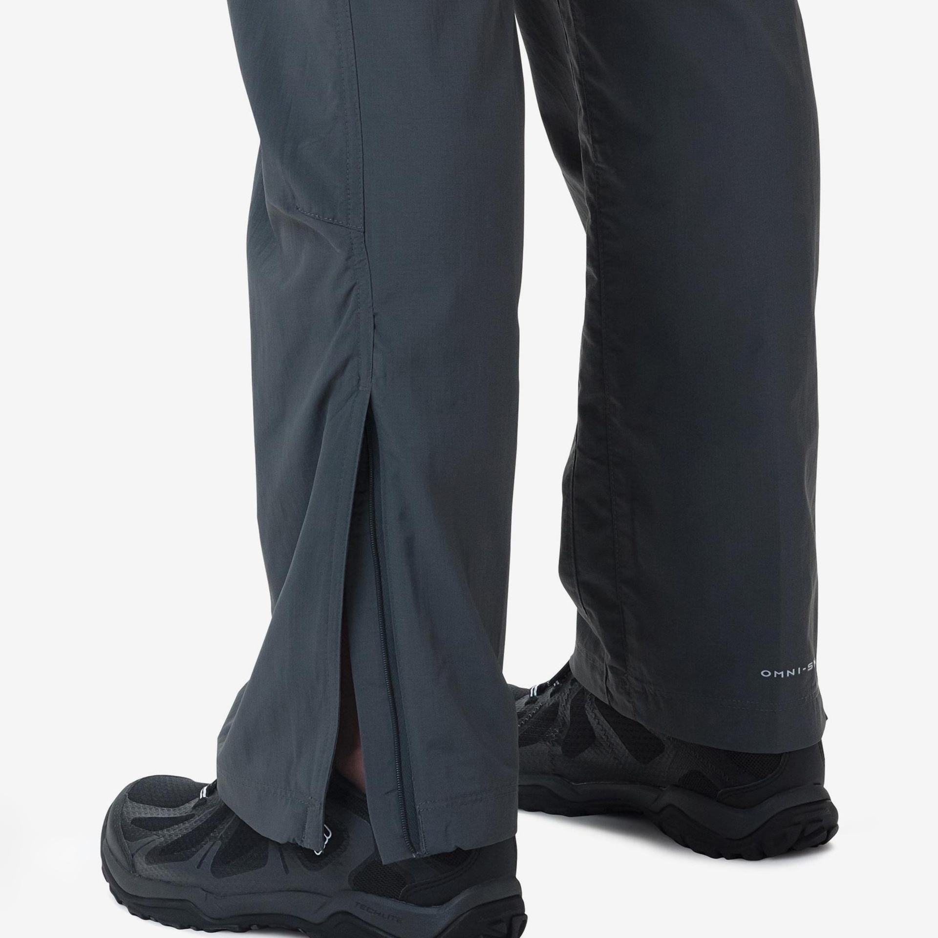 Calças técnicas cinza escuro com fecho junto a sapatilhas pretas.