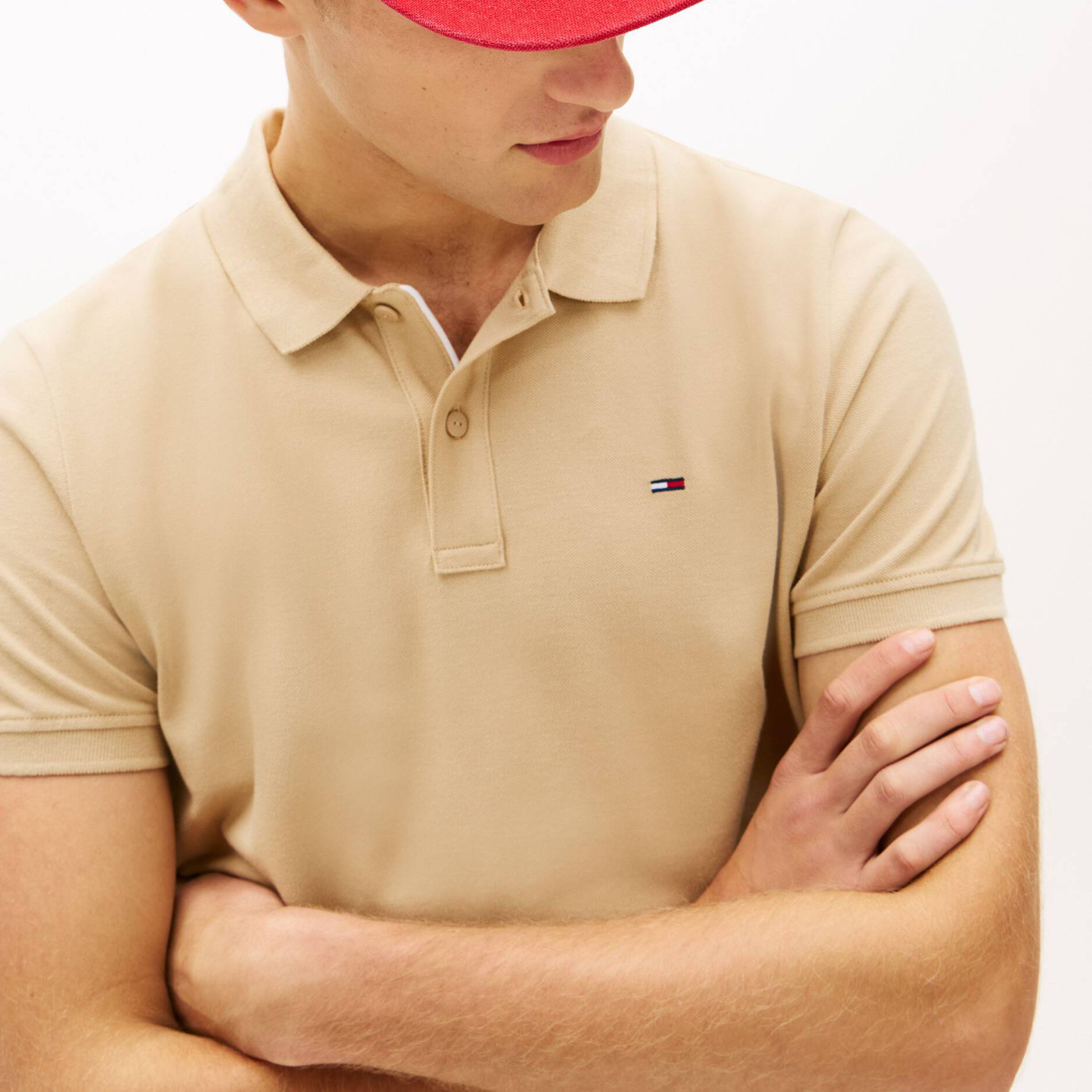 Polo bege Tommy Hilfiger e boné vermelho em fundo branco