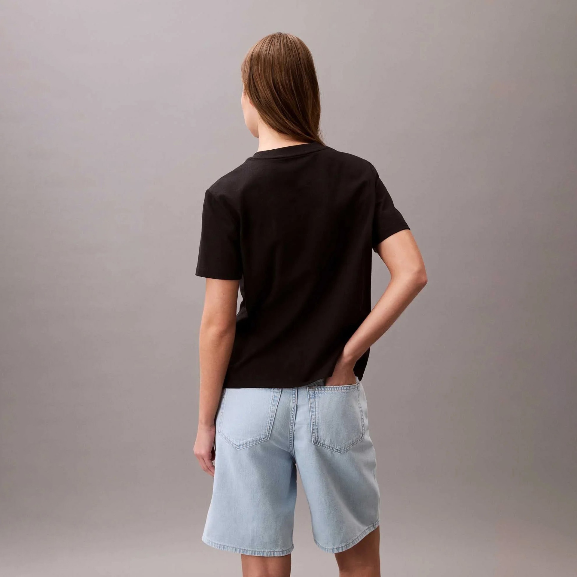 Mulher vista de costas vestindo t-shirt preta e calções de ganga azul claro