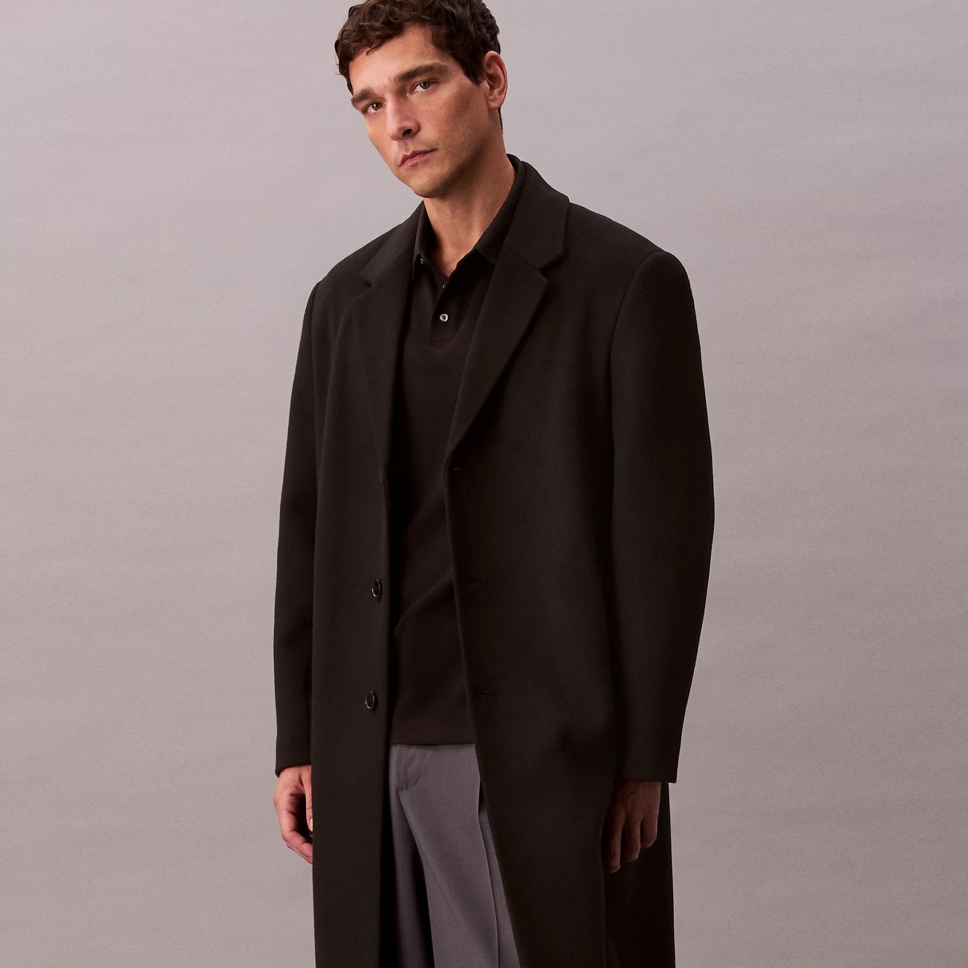 Homem com sobretudo preto comprido e camisa pólo preta