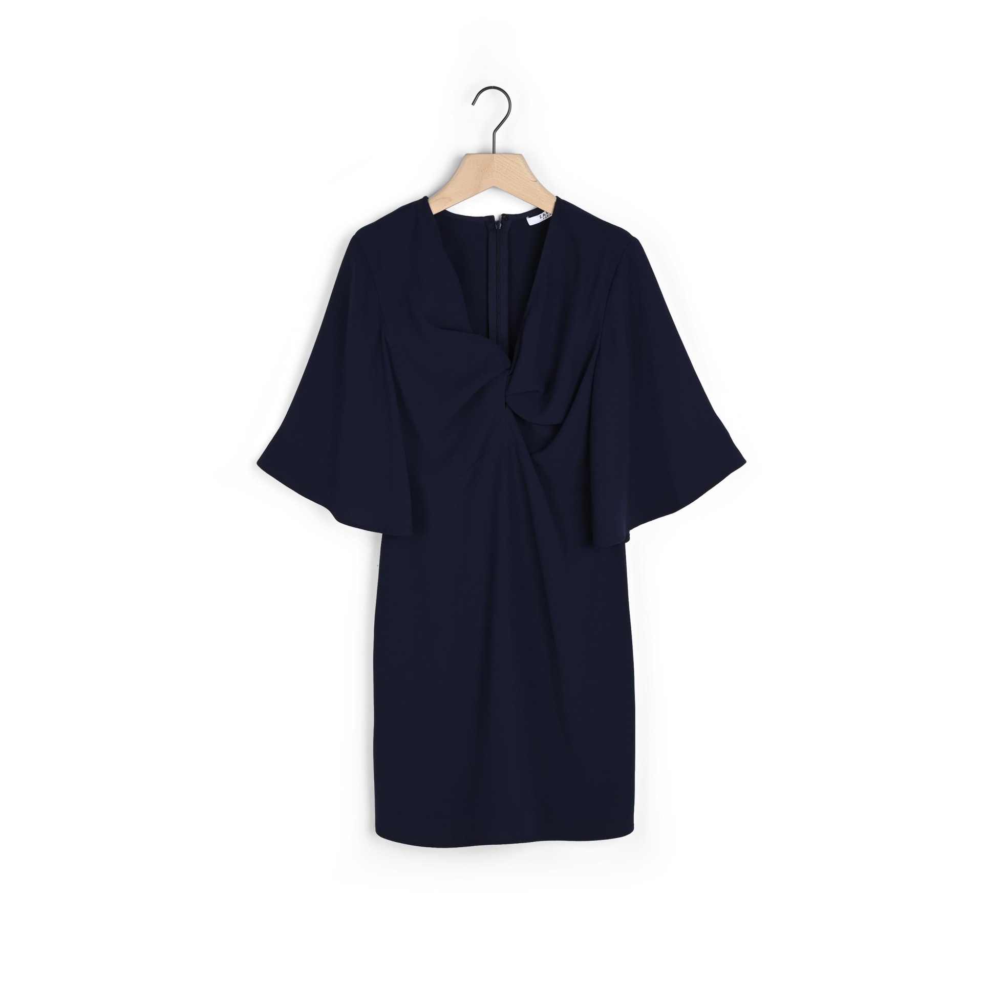 Vestido curto azul escuro com manga ampla e detalhes franzidos pendurado num cabide de madeira