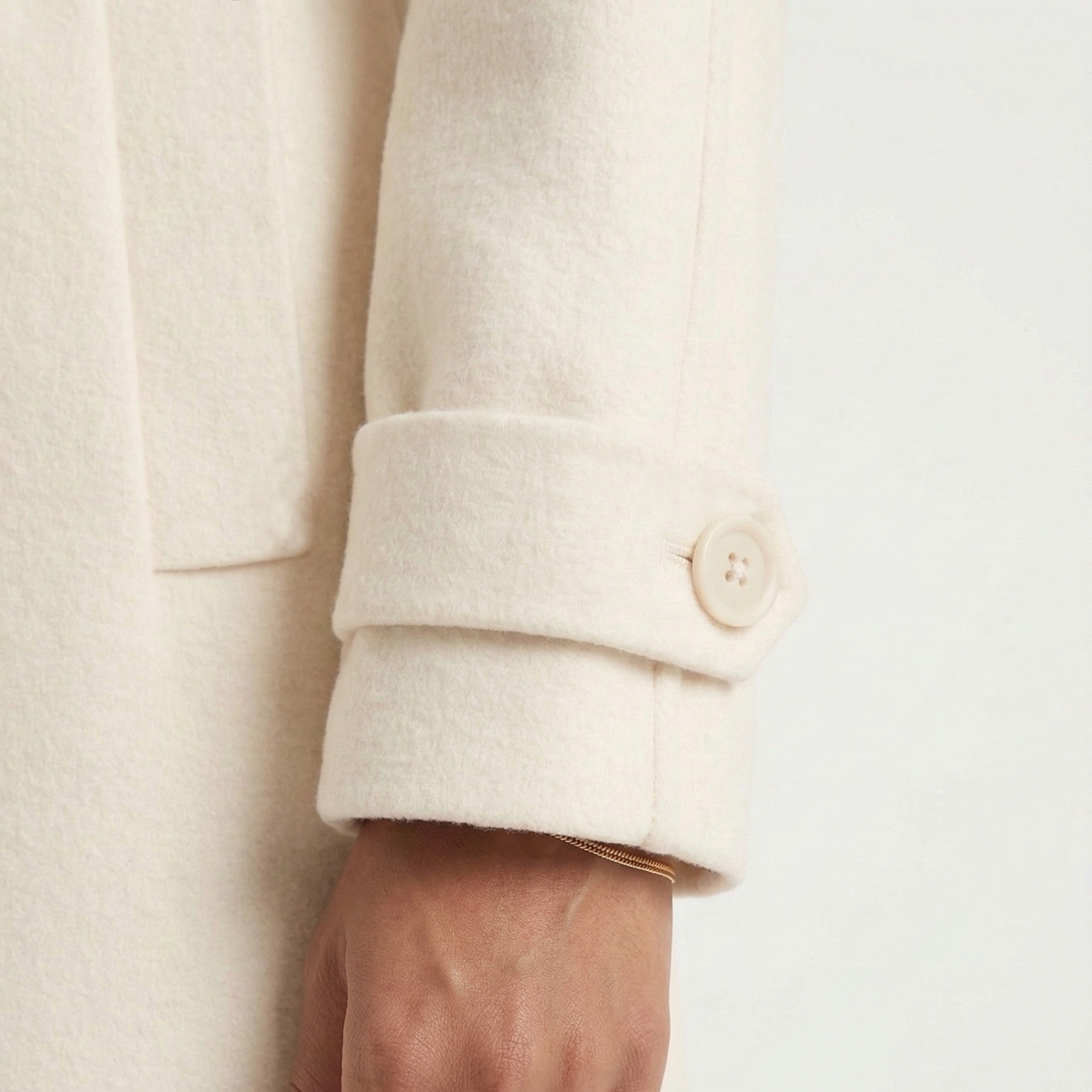 Manga de casaco branco creme com botão e bracelete dourado no pulso