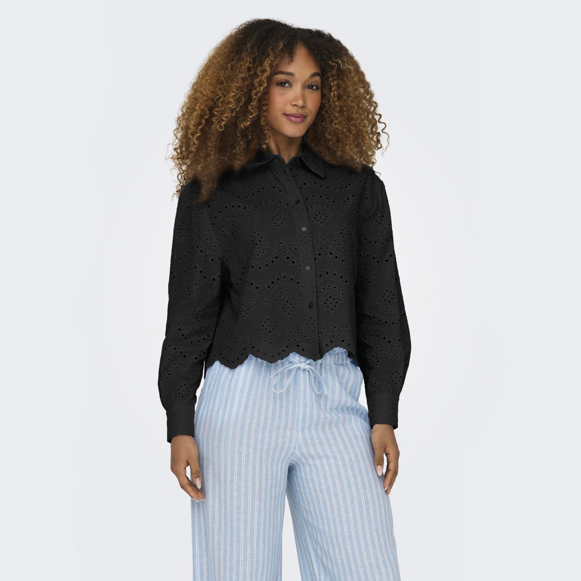 Camisa preta com padrão recortado e calças azuis às riscas