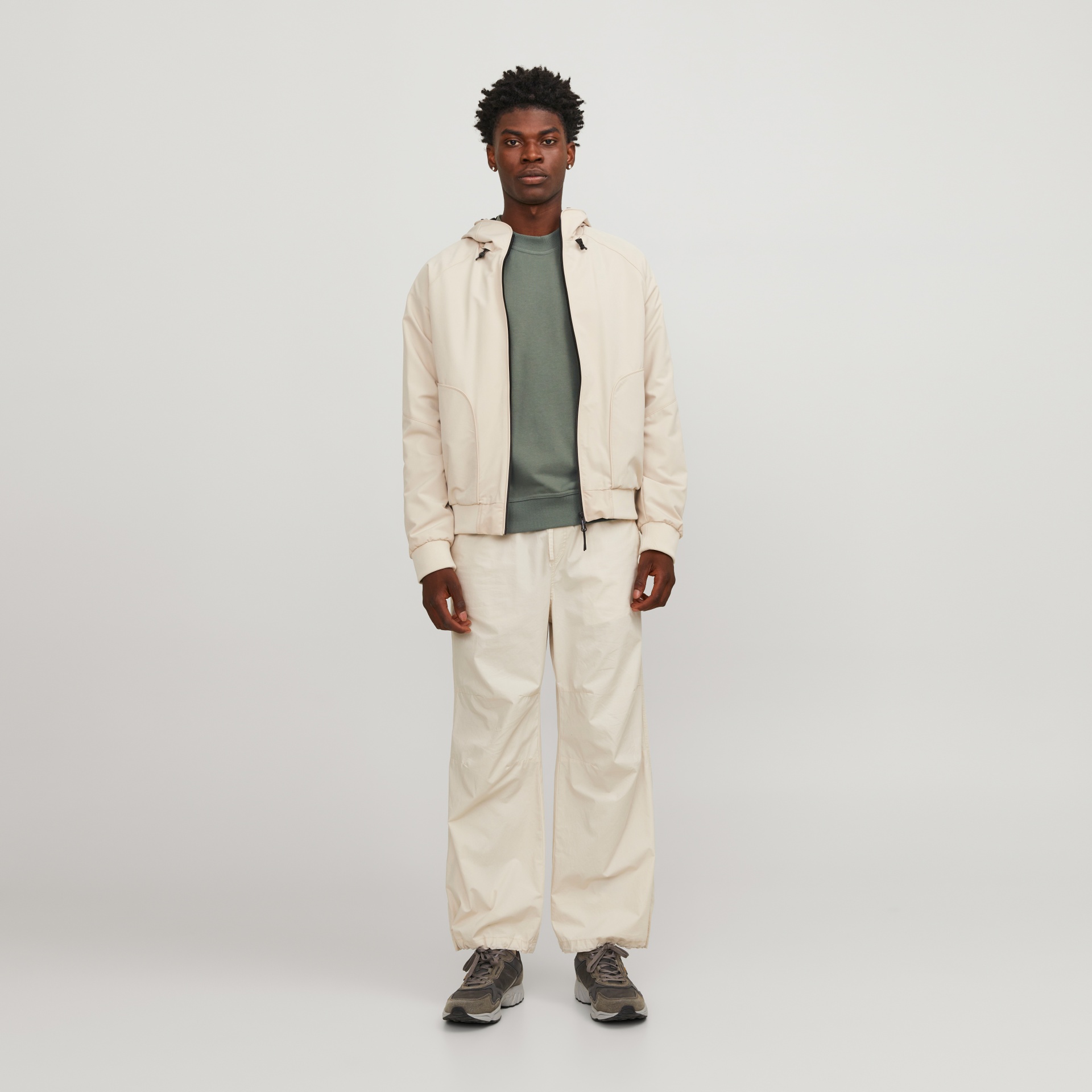 Homem com roupas casuais em tons bege e verde contra fundo branco