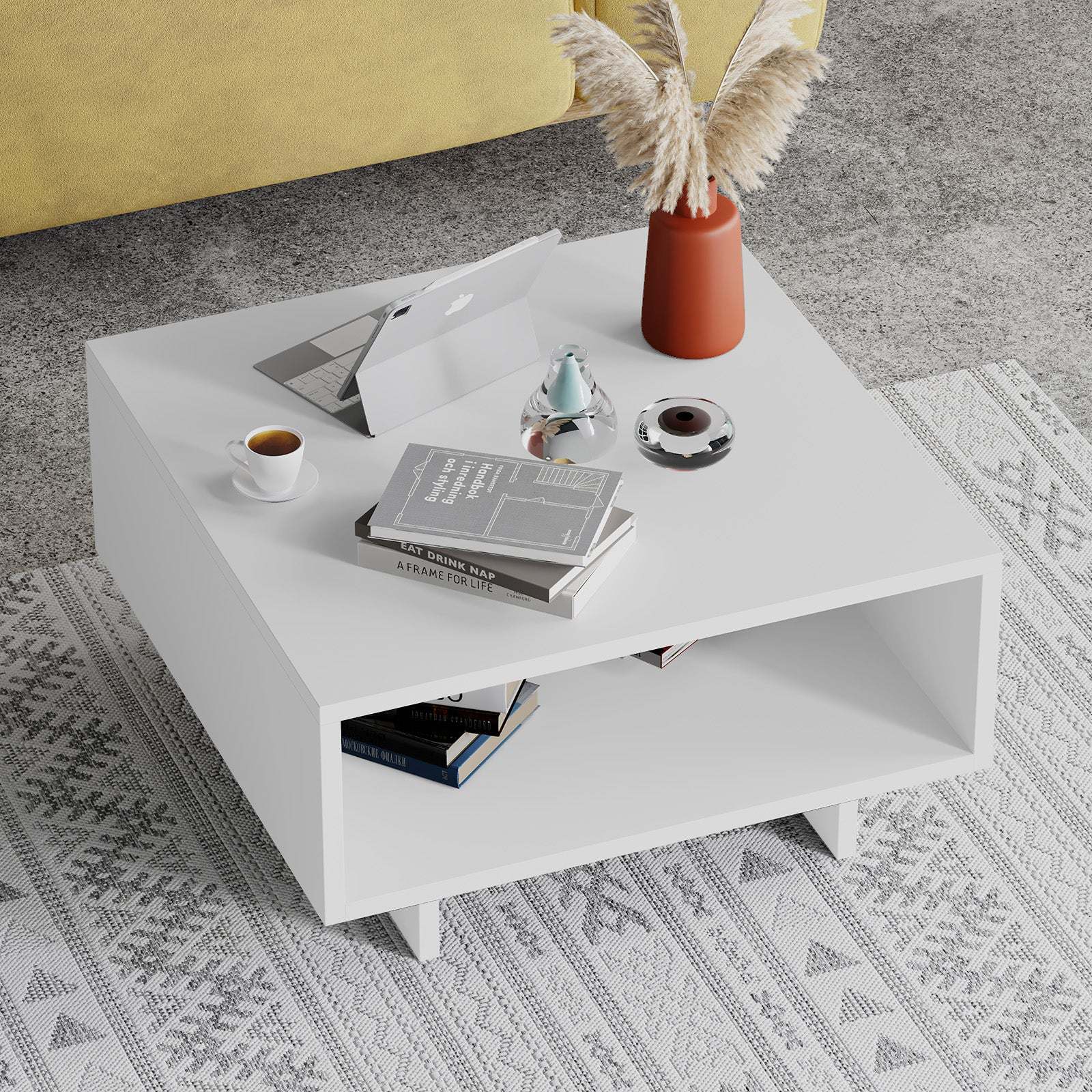 Mesa de centro branca com objetos e livros sobre tapete cinza