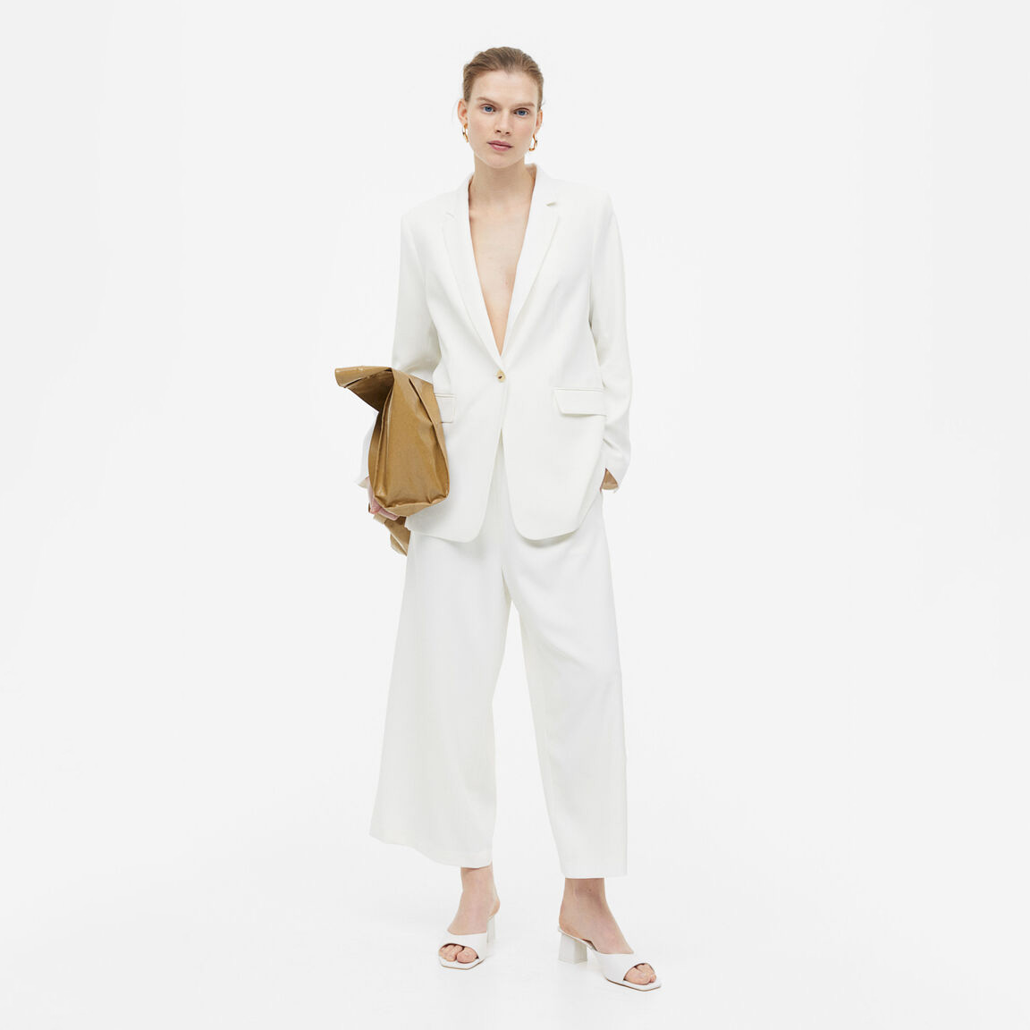 Conjunto feminino branco com blazer e calças largas, sapatos brancos e mala castanha