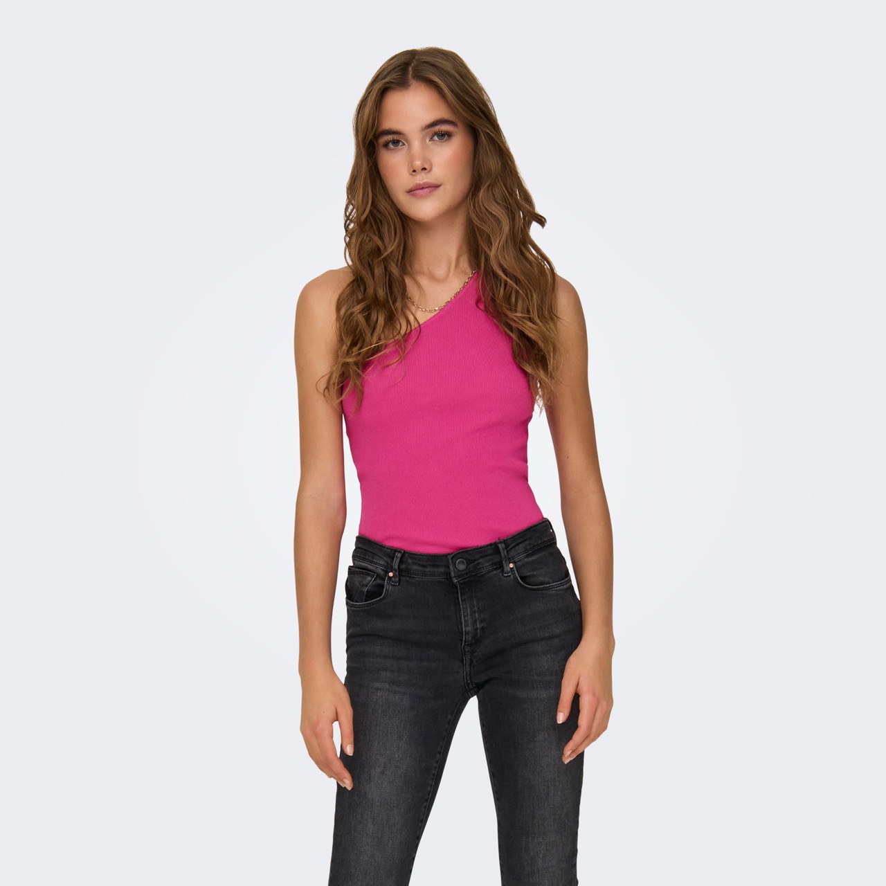 Mulher com blusa rosa fúcsia de um ombro e calças pretas de ganga