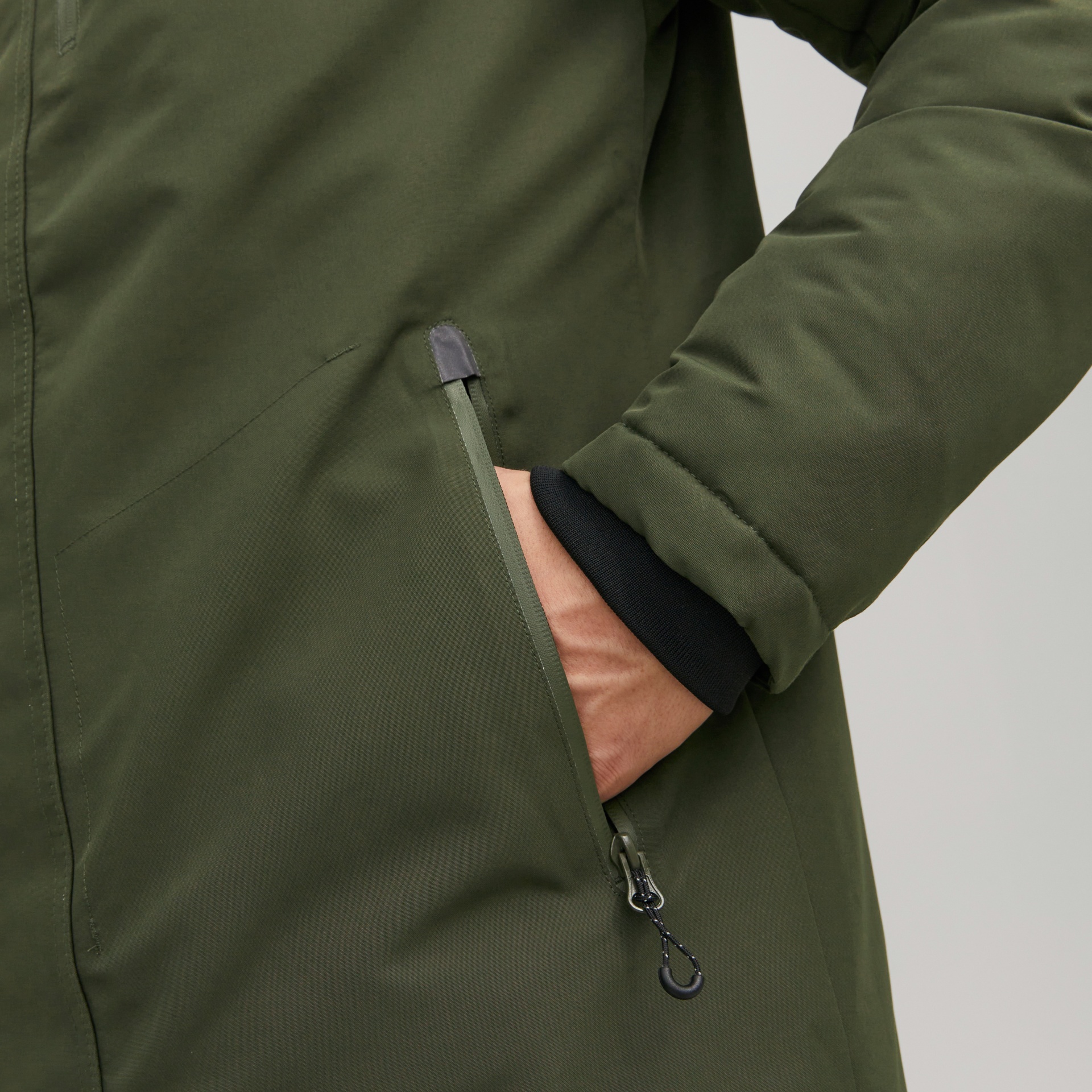 Casaco verde com bolso de fecho e punho preto numa das mangas