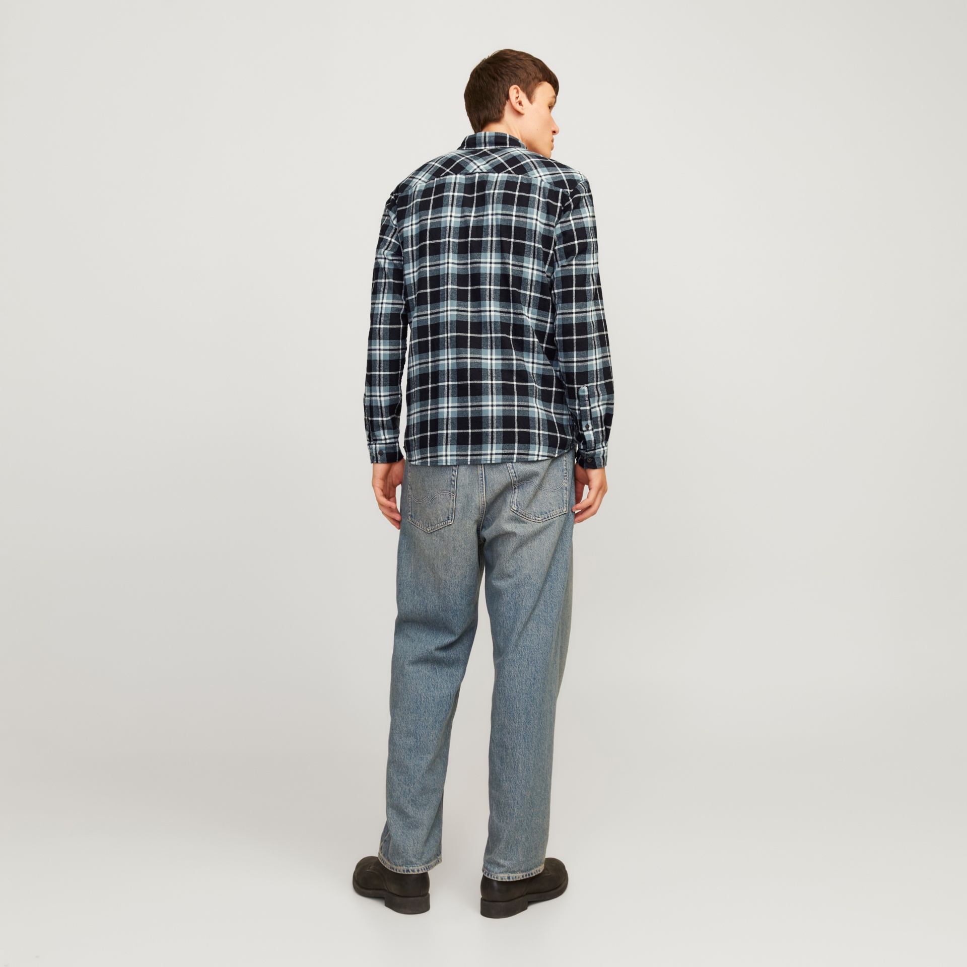 Homem de costas com camisa aos quadrados e calças de ganga azul claro