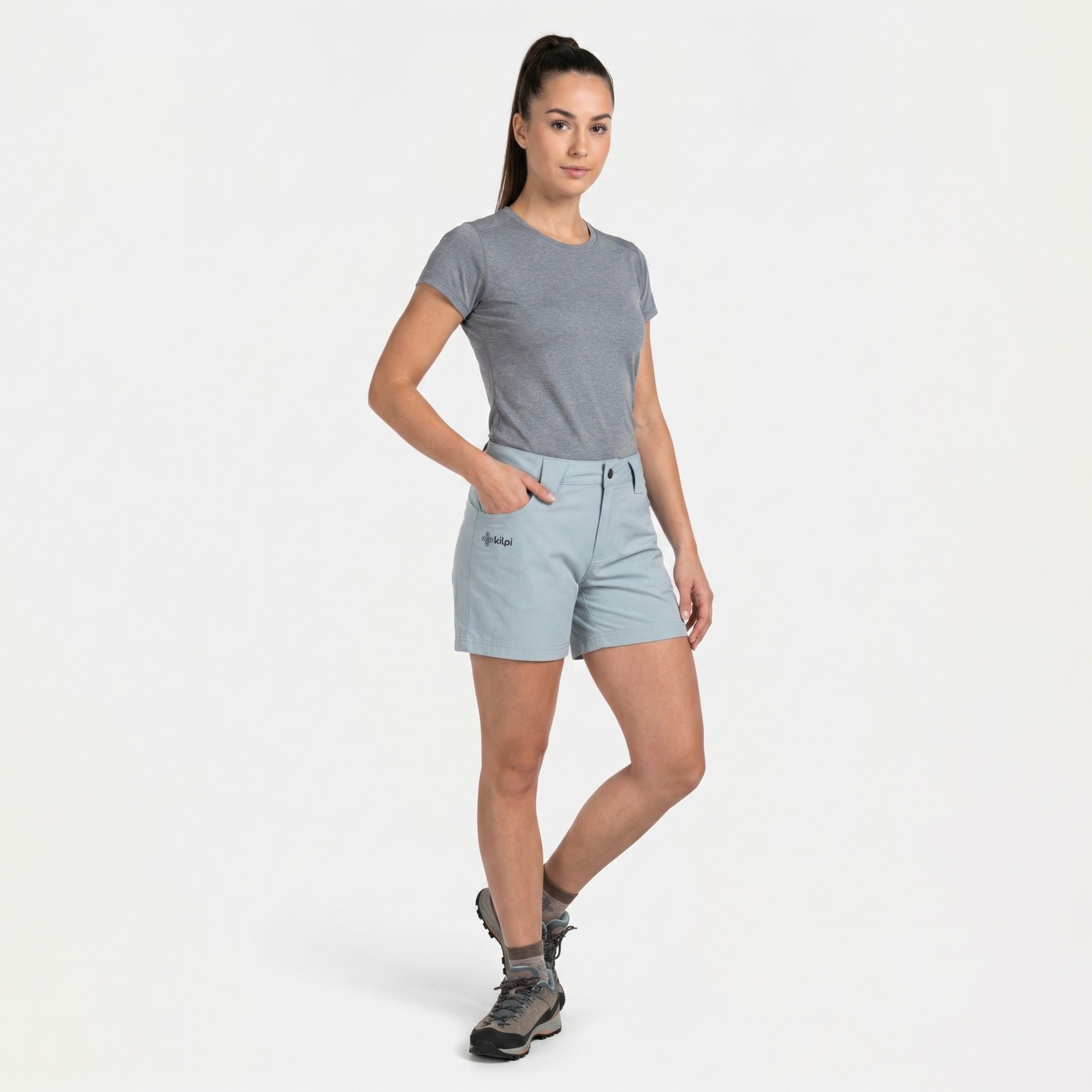 Mulher com calções azul claro e t-shirt cinza em fundo branco.