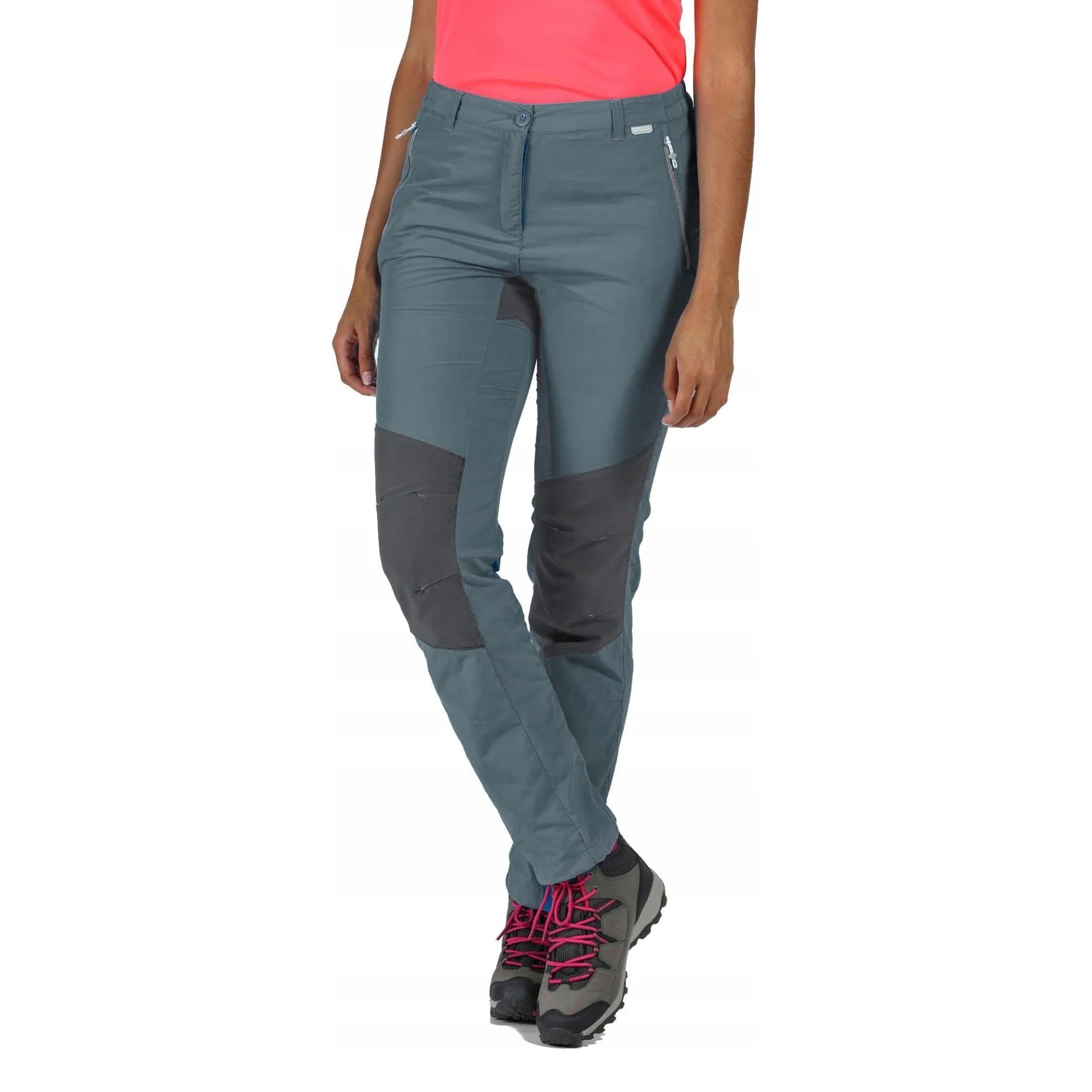 Calças de trekking cinza com reforços pretos e ténis cinzentos com atacadores cor de rosa.