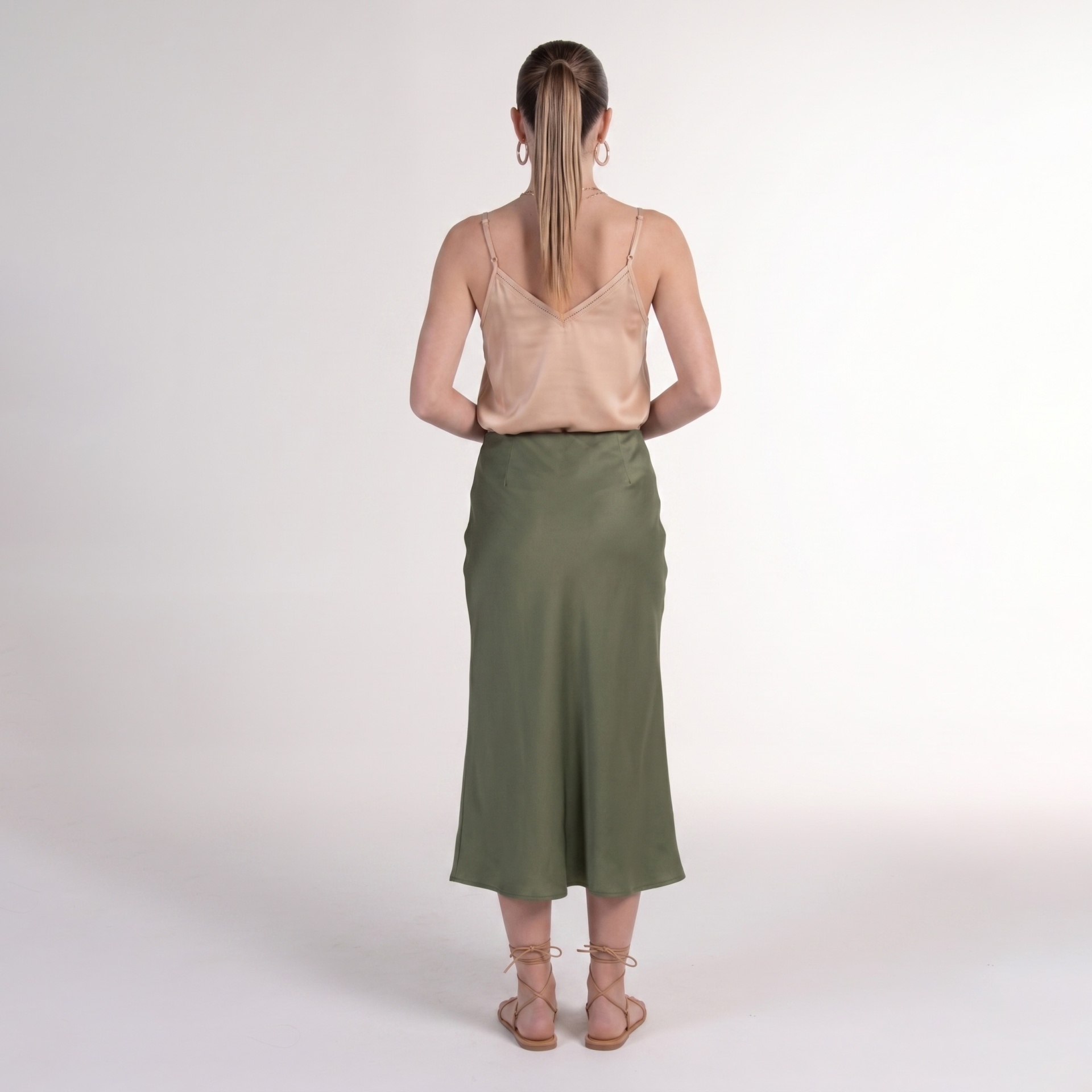 Pessoa de costas com vestido verde escuro e blusa bege clara