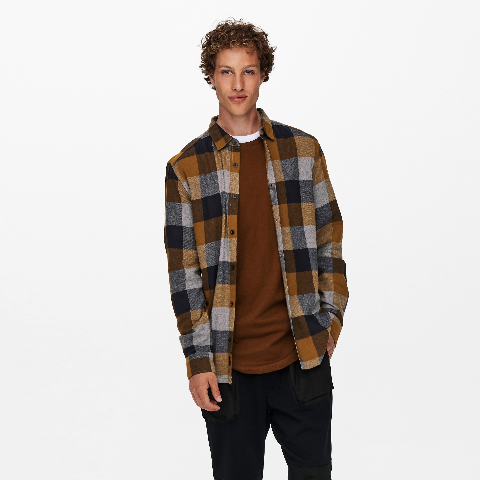 Camisola xadrez castanha, cinzenta e preta com botões pretos sobre t-shirt castanha.