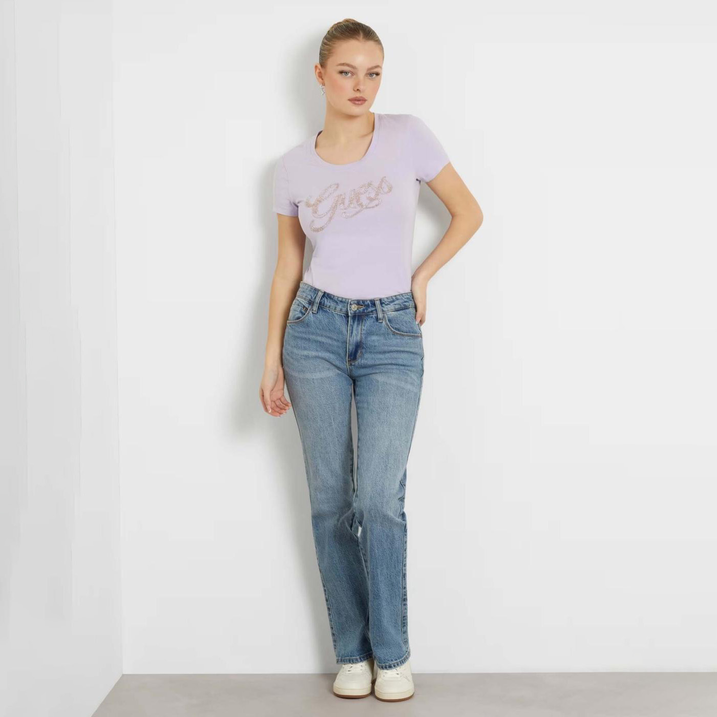 Mulher com t-shirt lilás e jeans azul claro em fundo branco