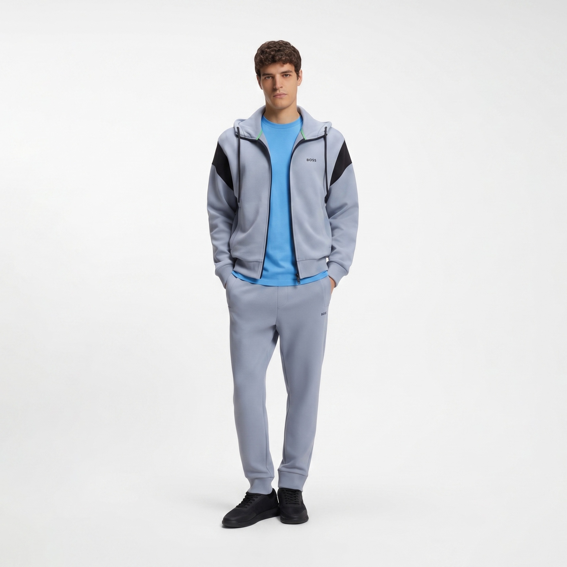 Homem vestido com conjunto desportivo azul claro e preto, com t-shirt azul e sapatilhas pretas