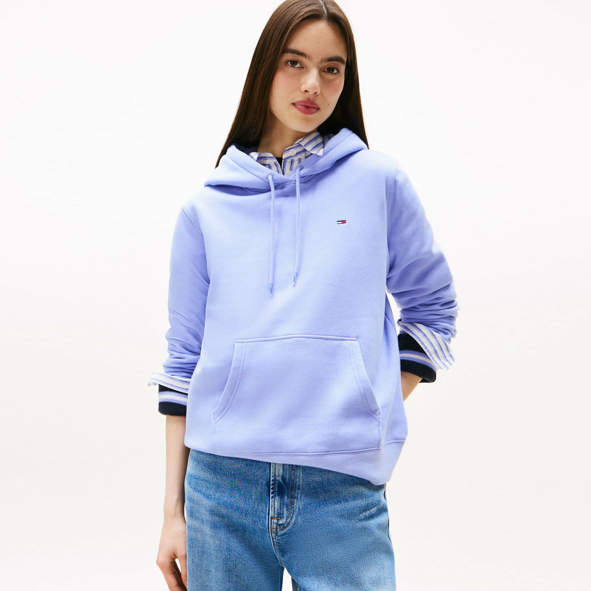 Sweatshirt azul claro com capuz e bolso canguru, usada com camisa às riscas e calças de ganga