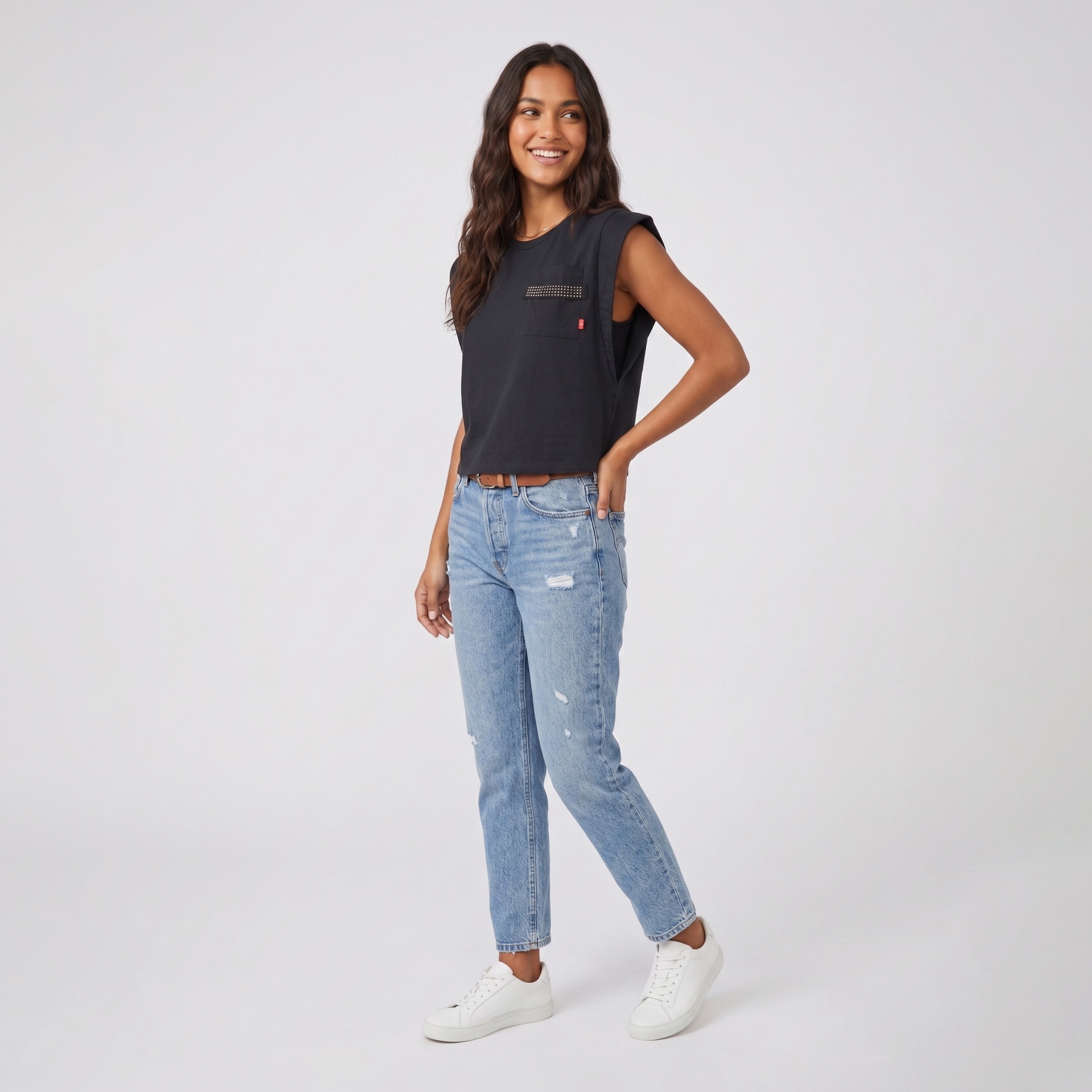 Mulher com top preto e jeans azuis claros em fundo branco.