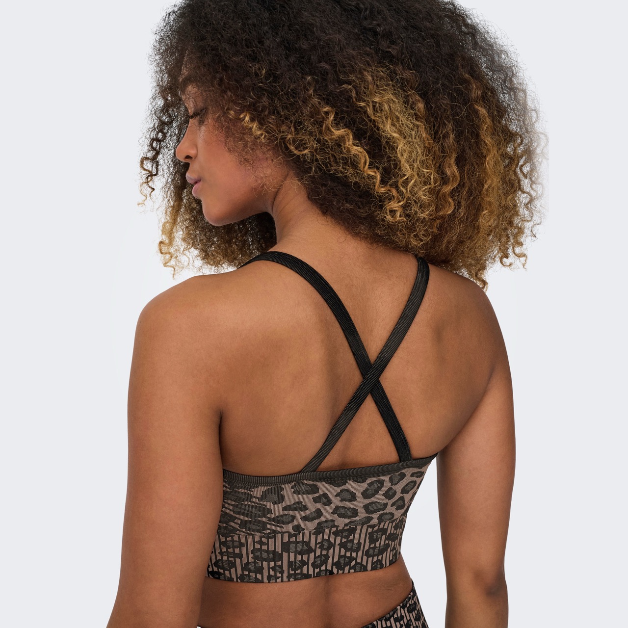 Top desportivo feminino com padrão animal print e alças cruzadas pretas