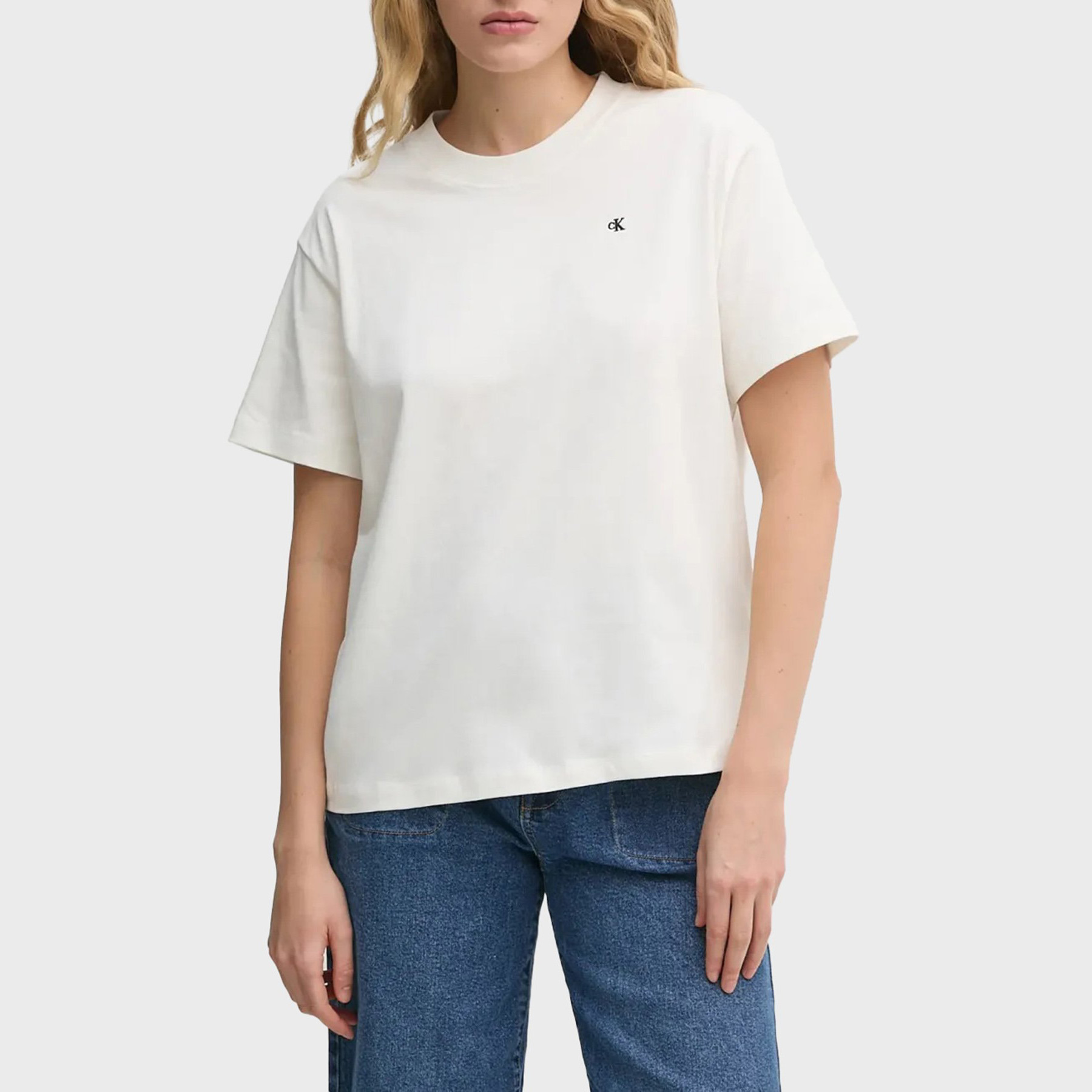 T-shirt branca com símbolo CK bordado, usada com calças de ganga azuis