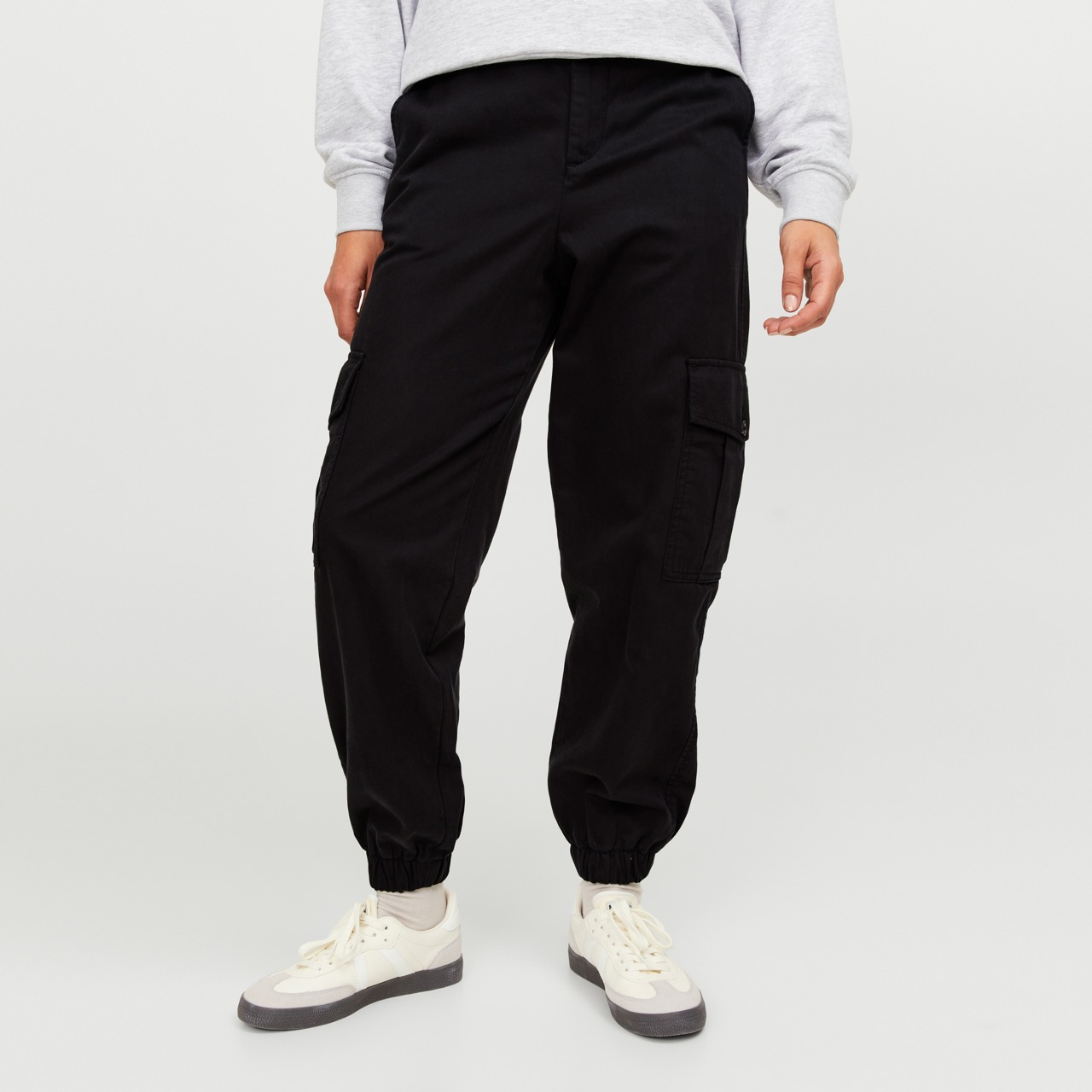 Calças cargo pretas com bolso lateral e sapatilhas brancas