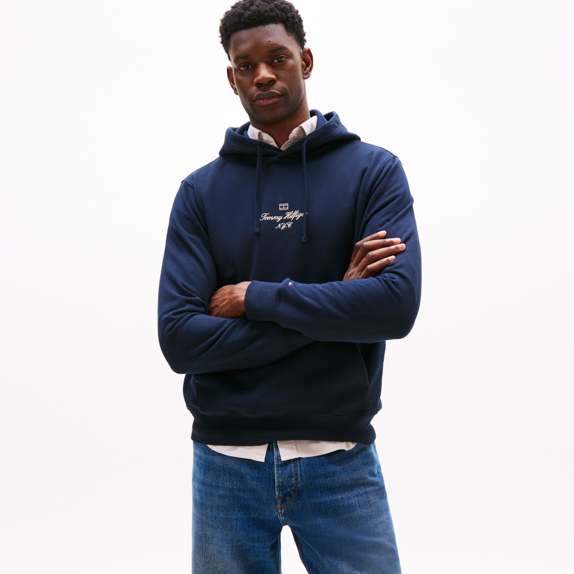 Homem a usar sweatshirt azul escuro Tommy Hilfiger com capuz e texto bordado no peito