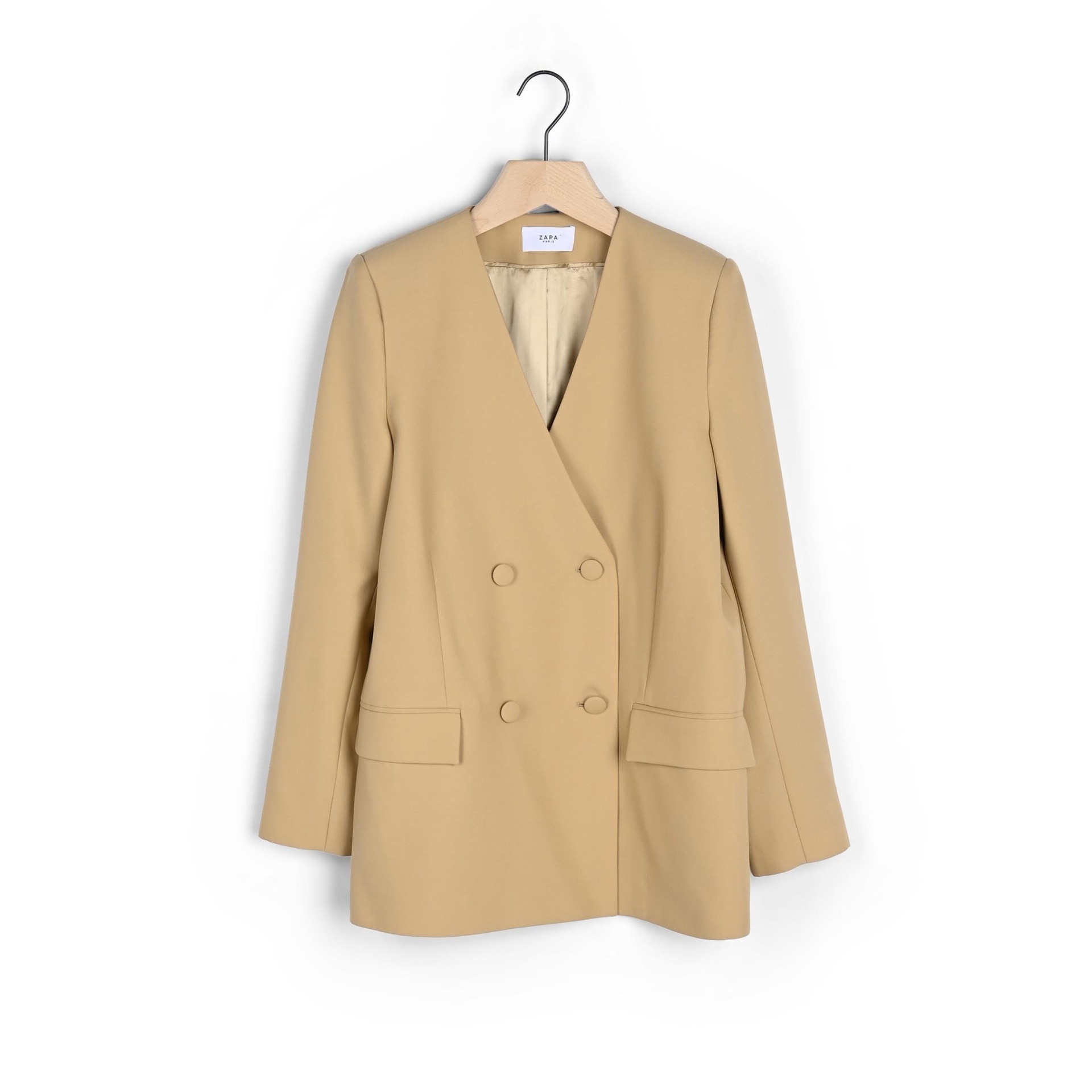 Blazer bege feminino com abotoação dupla pendurado num cabide