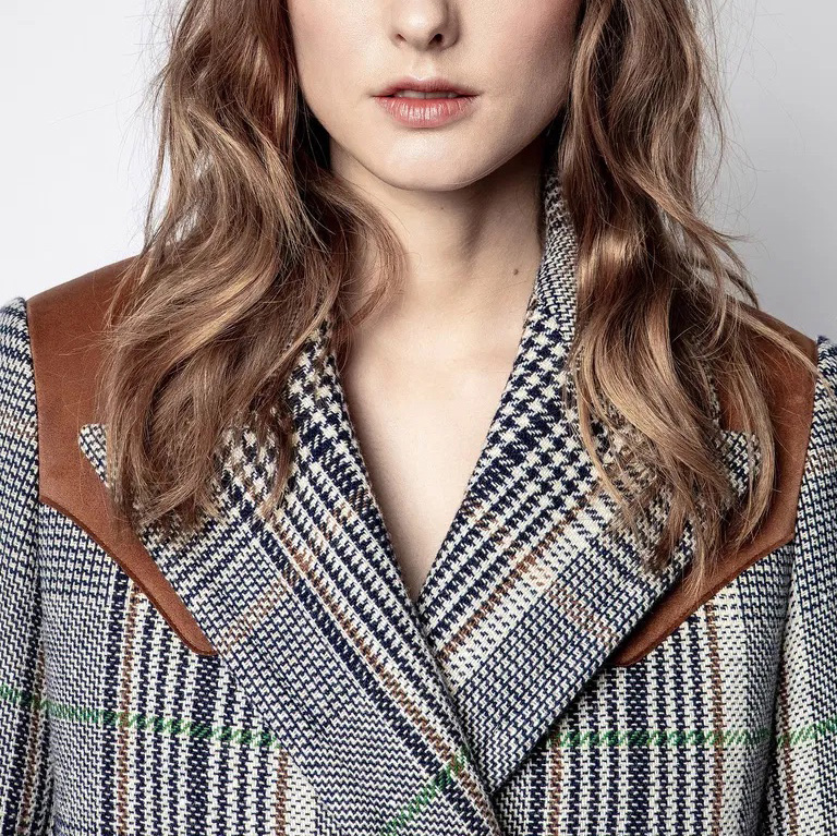 Casaco feminino com padrão pied-de-poule e detalhes em tecido castanho nos ombros.