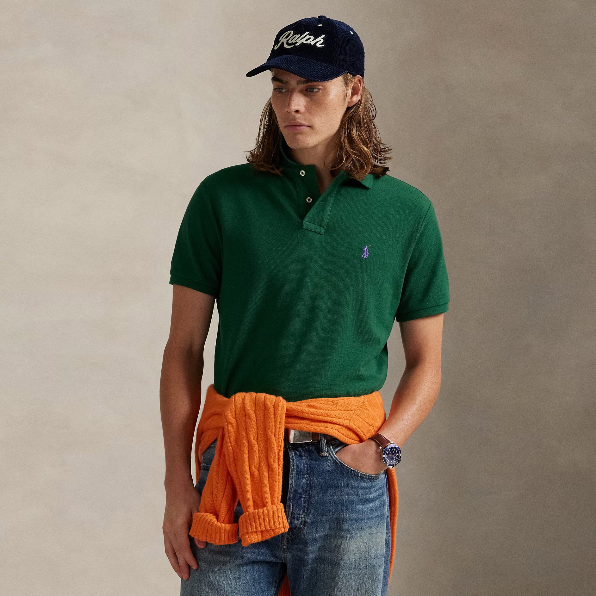 Homem com polo verde e cardigan laranja amarrado na cintura