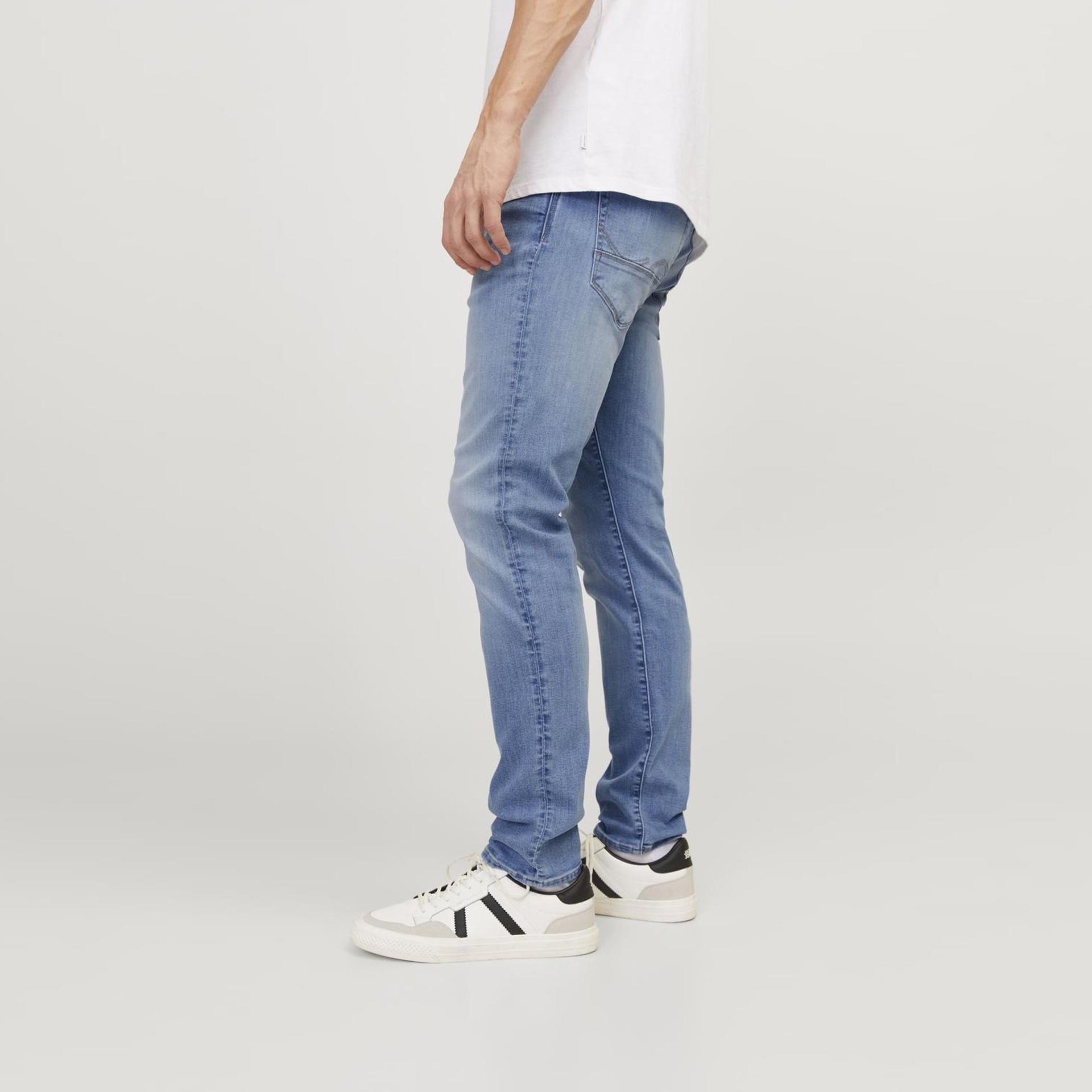 Calças jeans azuis justas com sapatilhas brancas e pretas