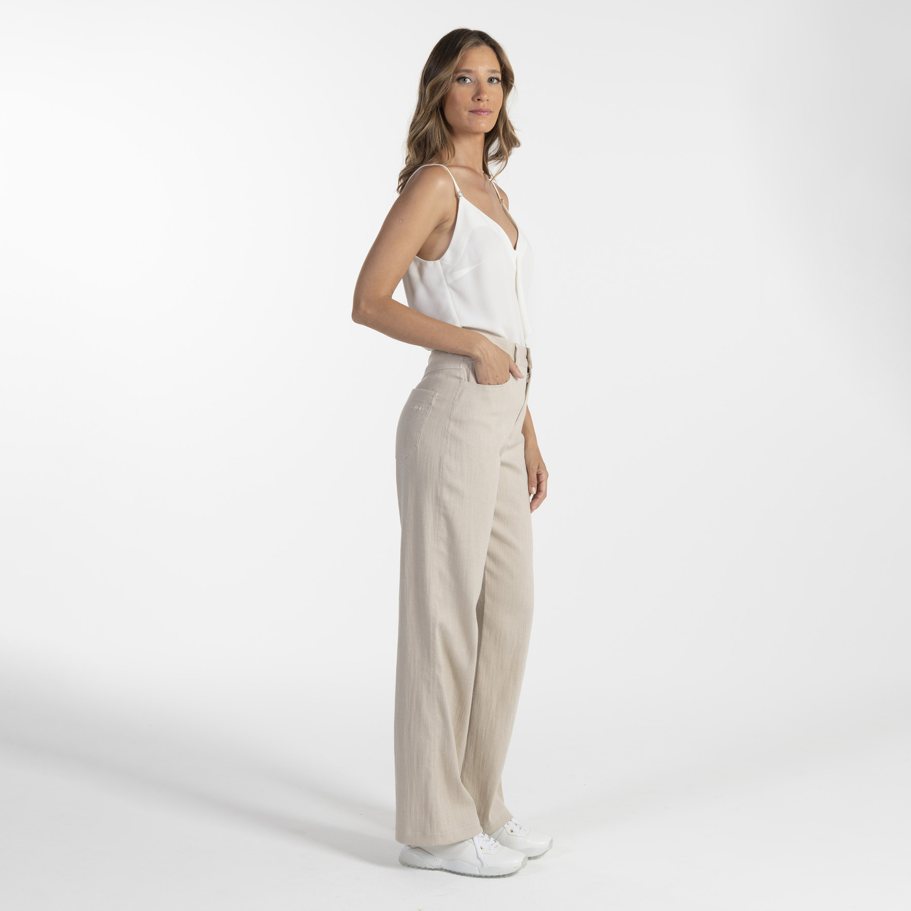 Mulher de perfil com roupa clara em fundo branco