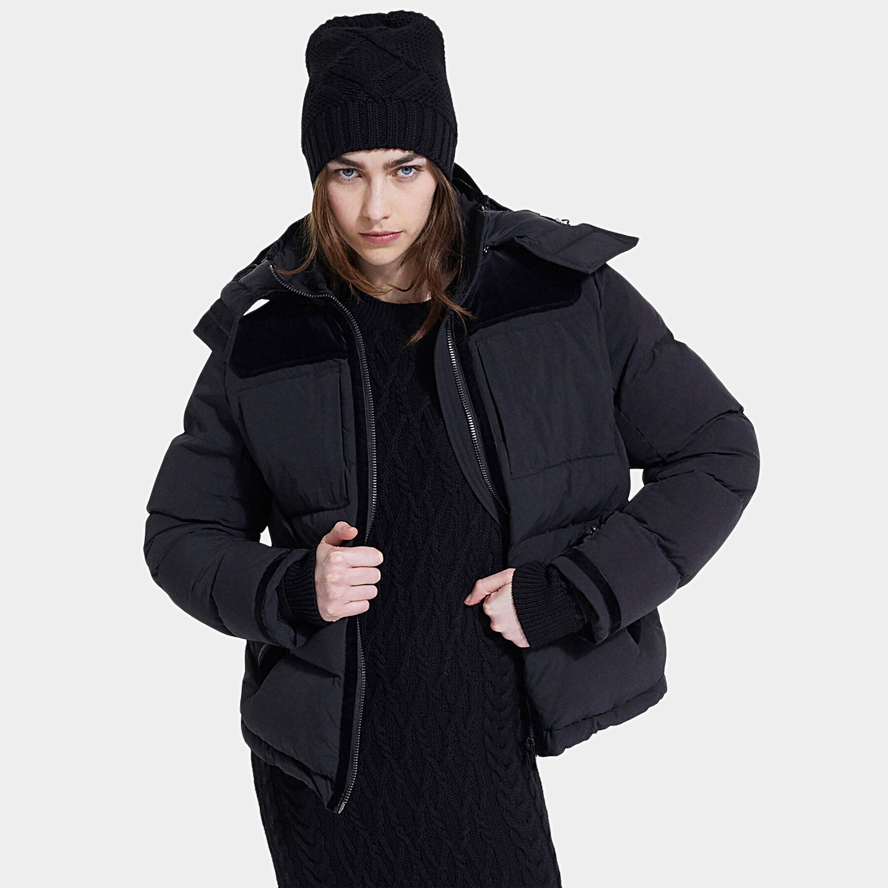 Mulher com casaco acolchoado preto, vestido e gorro de malha pretos