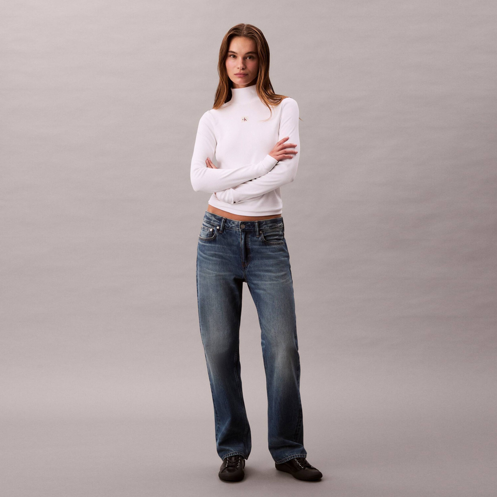 Blusa branca gola alta e calças de ganga azuis com sapatos pretos