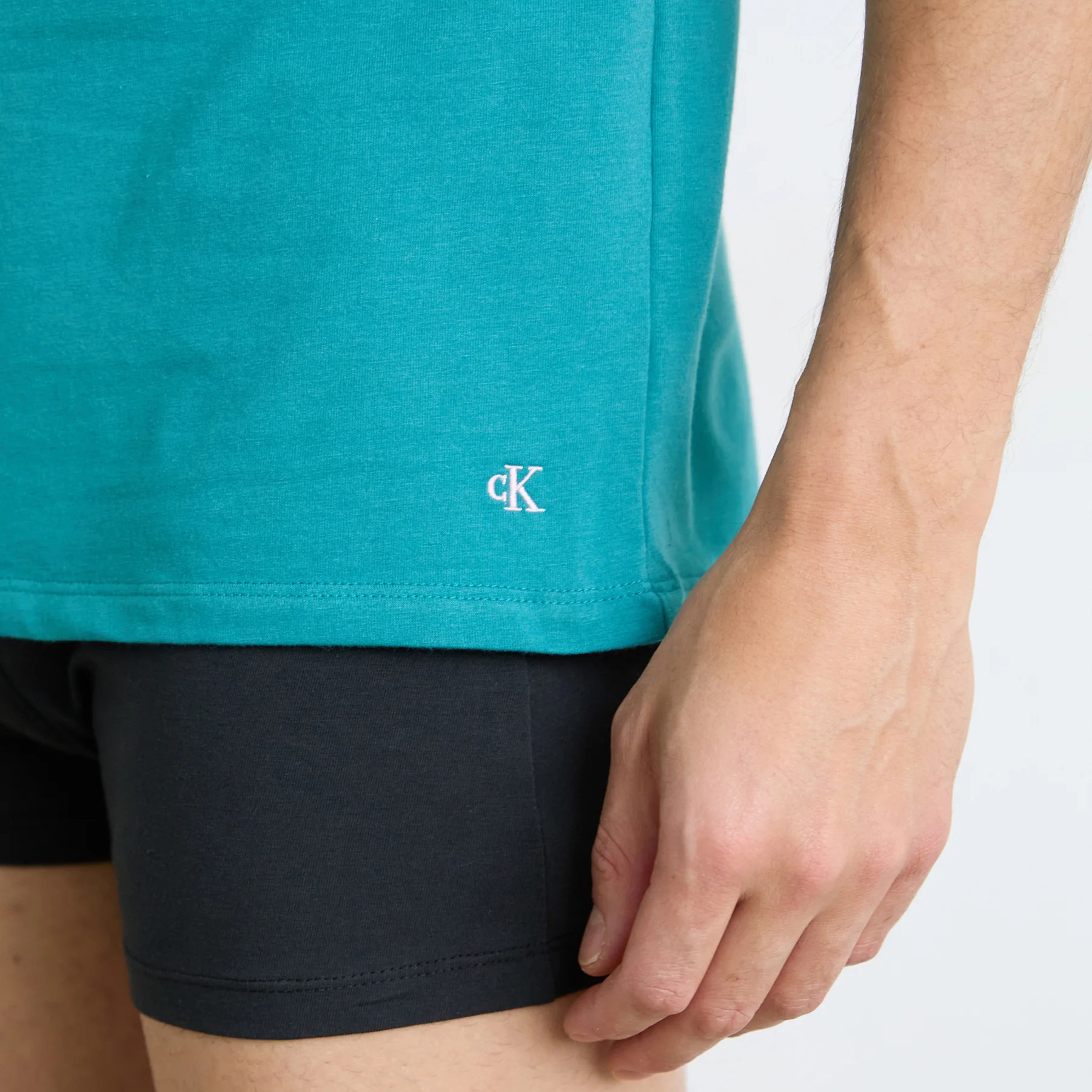 Camisola azul turquesa com logo cK e calções pretos em pessoa