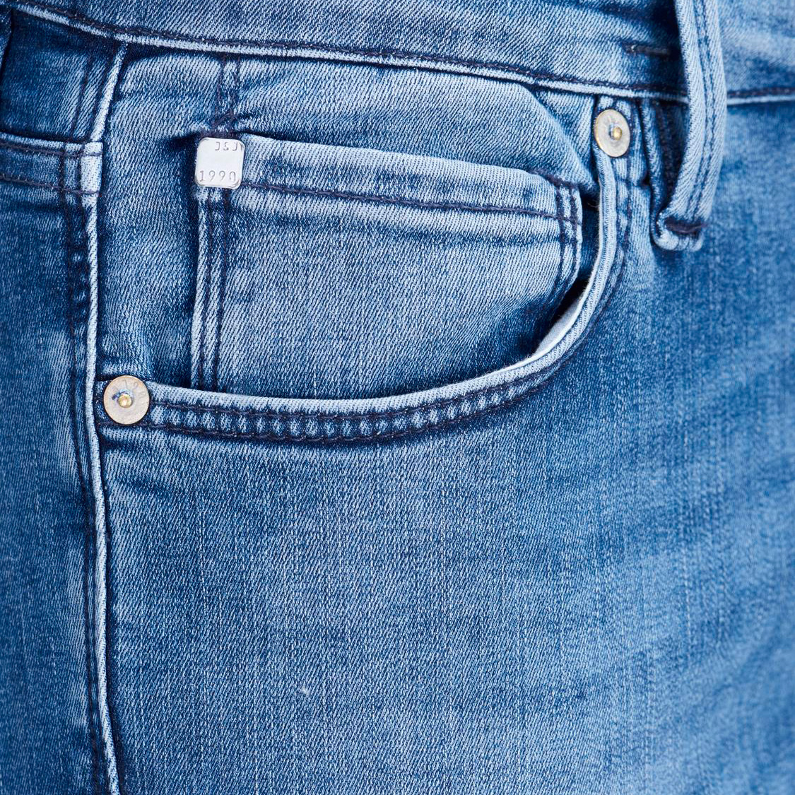 Bolso de calças de ganga azuis com etiqueta branca e rebites metálicos