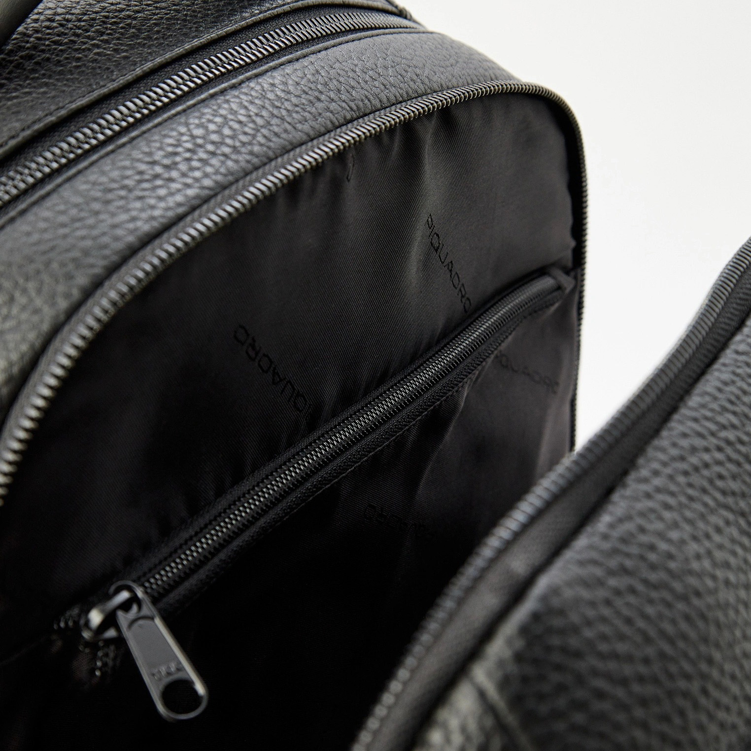Interior de mochila preta de pele com tecido estampado QUILIADRO e fecho de correr preto