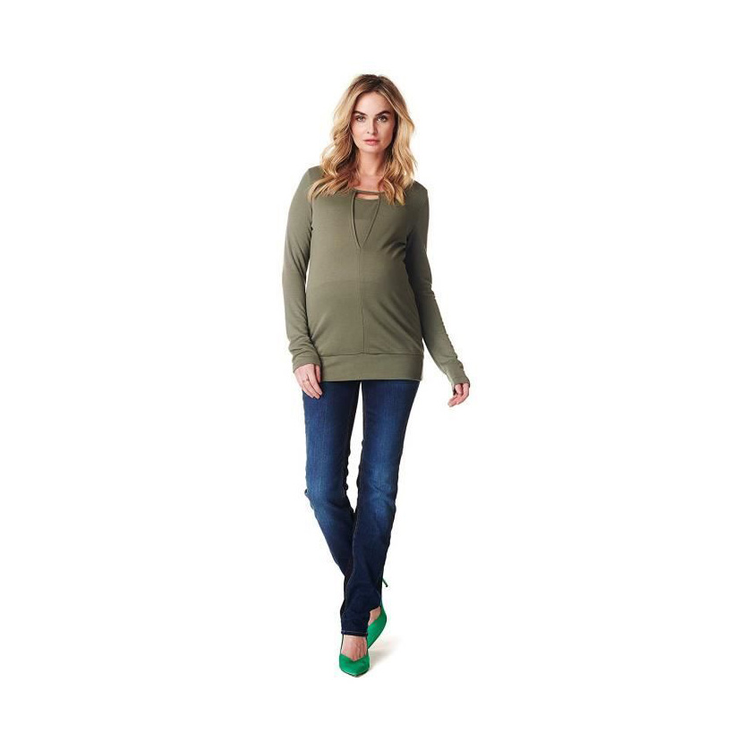 Mulher a usar camisola verde-oliva, calças de ganga azul escuro e sapatos verdes em fundo branco