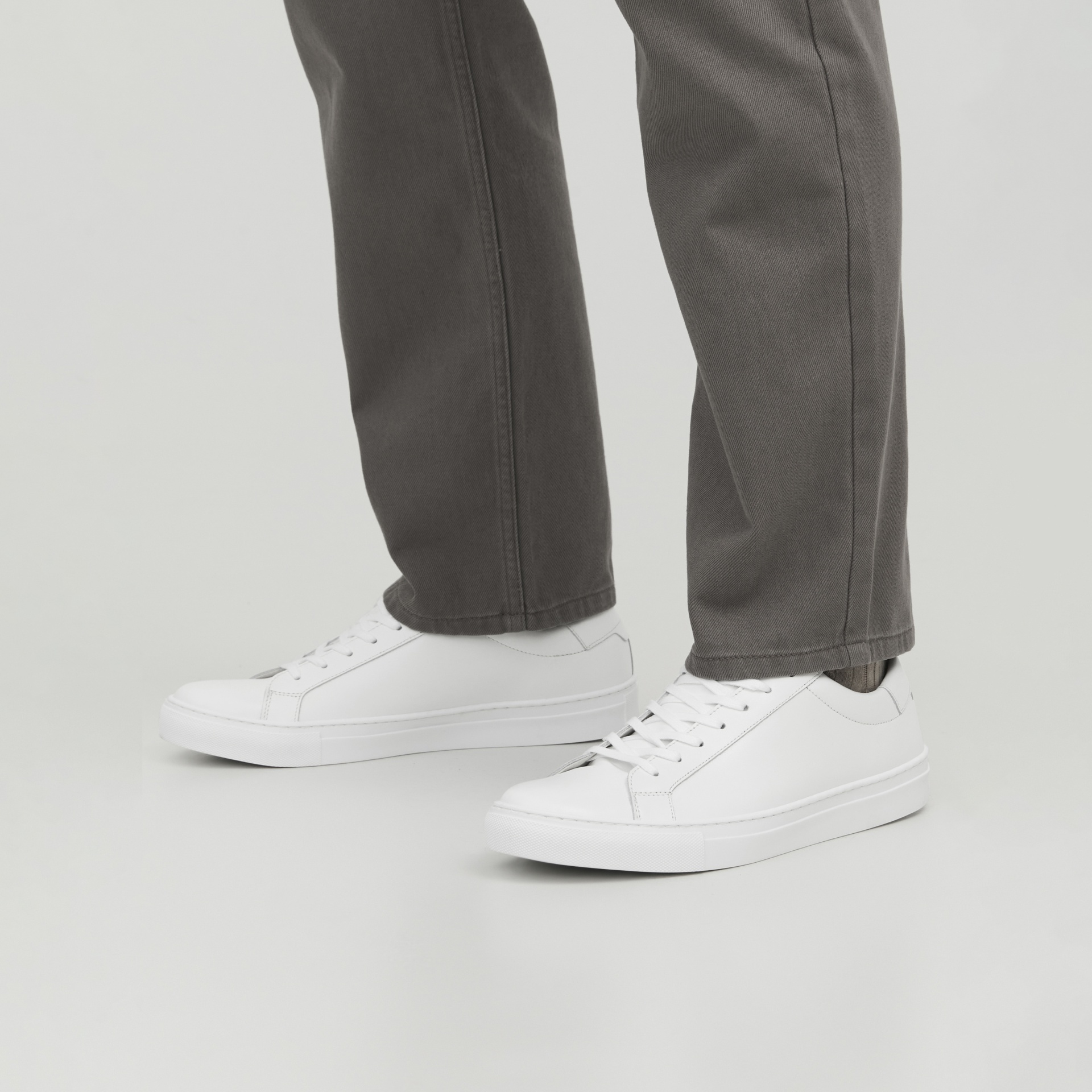 Sapatos desportivos brancos com calças cinzentas