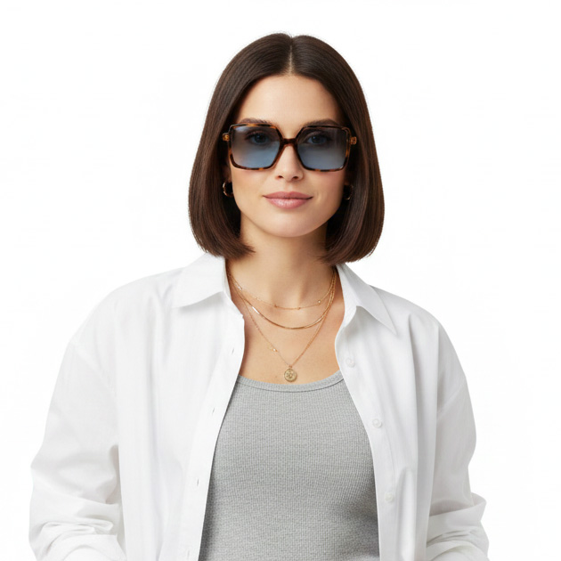 Mulher com camisa branca, top cinza, óculos de sol quadrados castanhos e colares dourados.