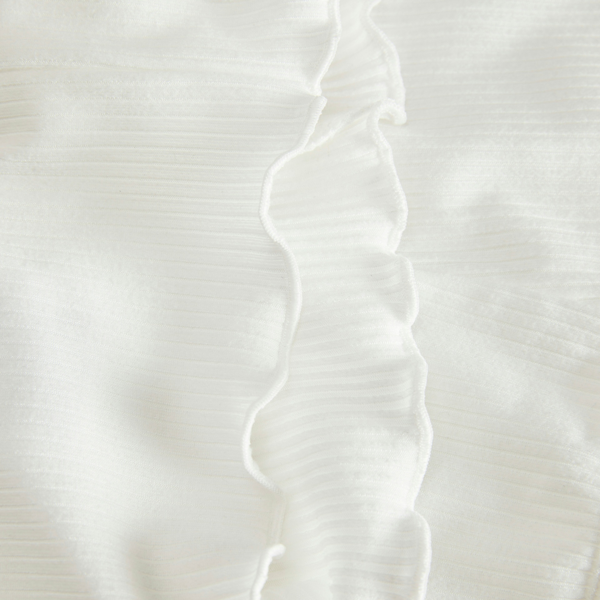 Close-up de tecido branco com textura riscada e babados ao centro