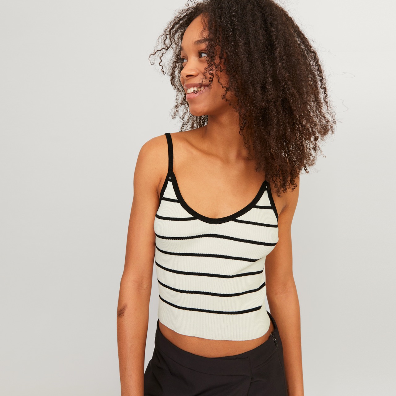 Top branco canelado com listras negras e alças finas num ambiente neutro