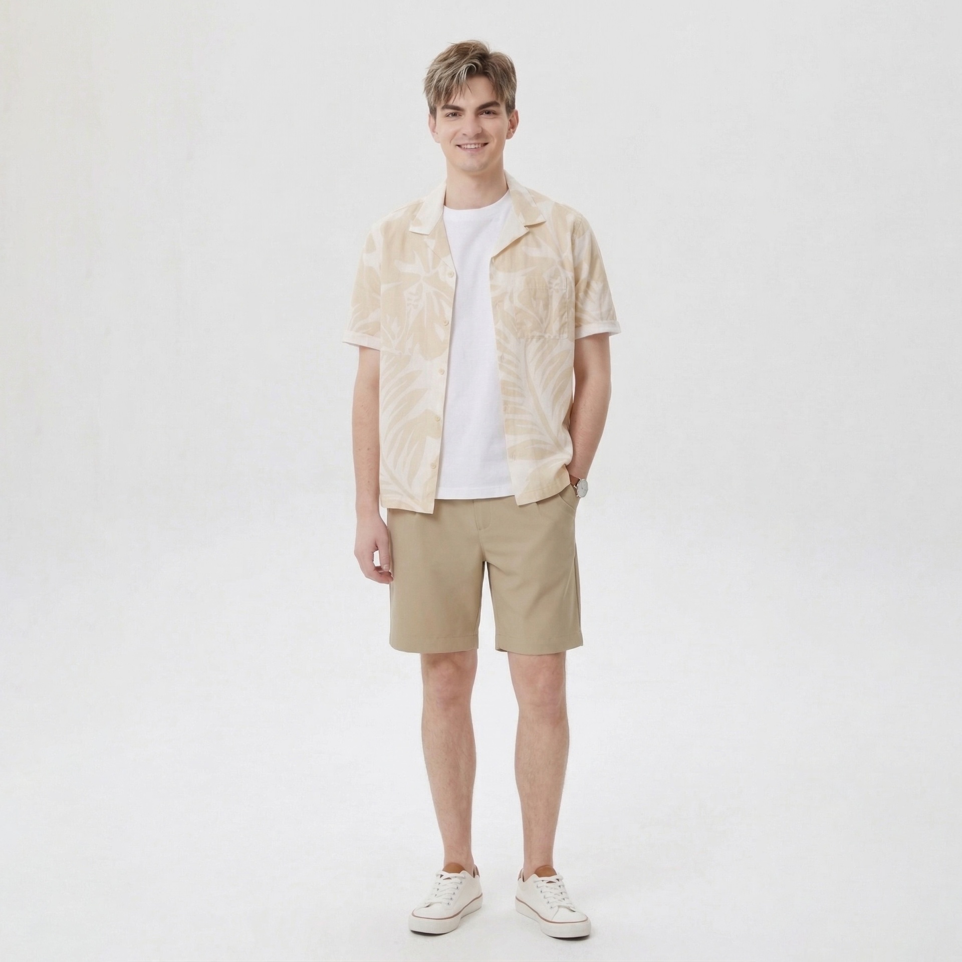 Homem jovem com camisa bege floral, t-shirt branca, calções bege e ténis brancos