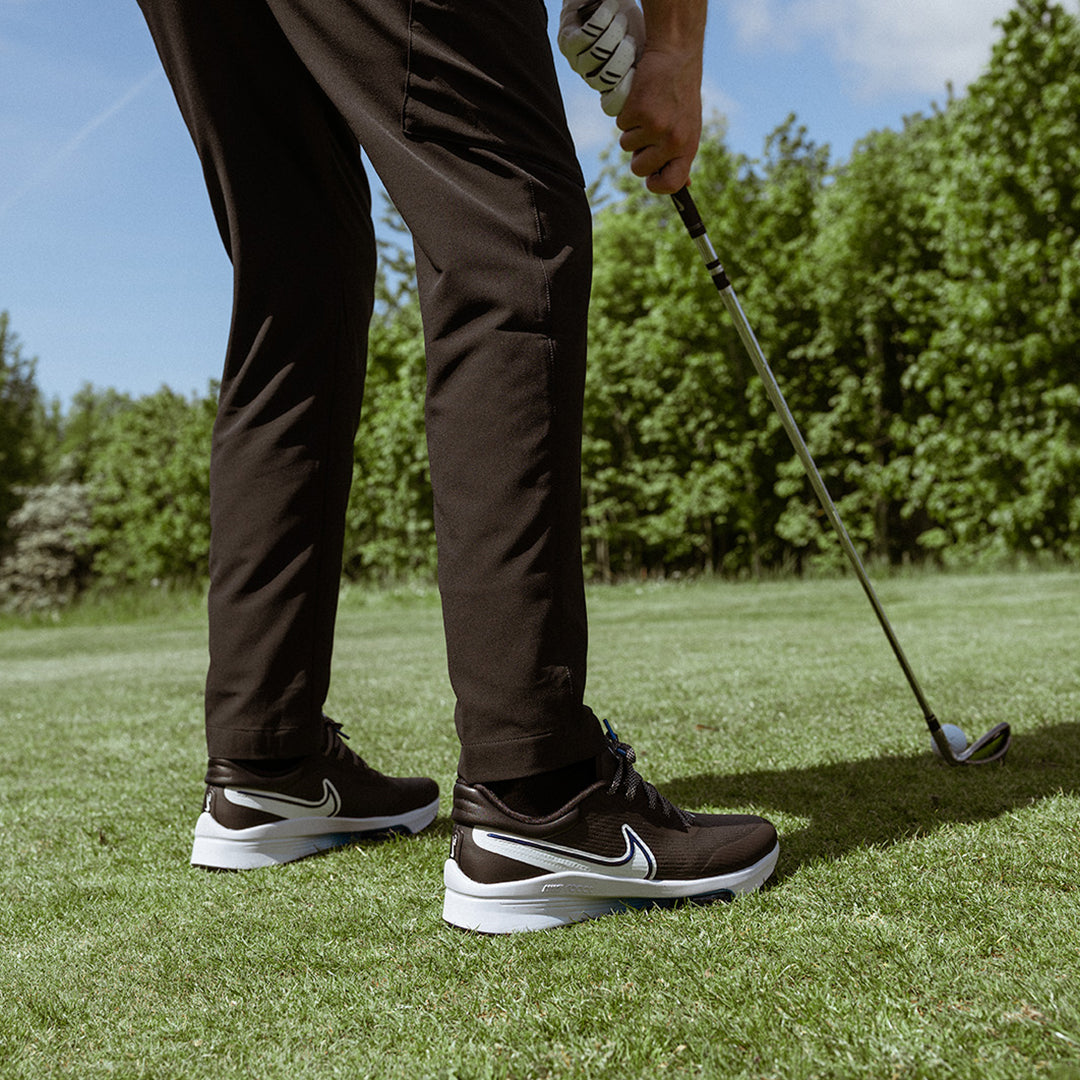 Sapatos desportivos pretos com sola branca e logo Nike branco em relva de golfe