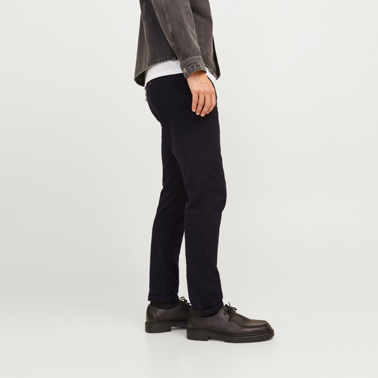 Calças pretas ajustadas com sapatos pretos em fundo branco