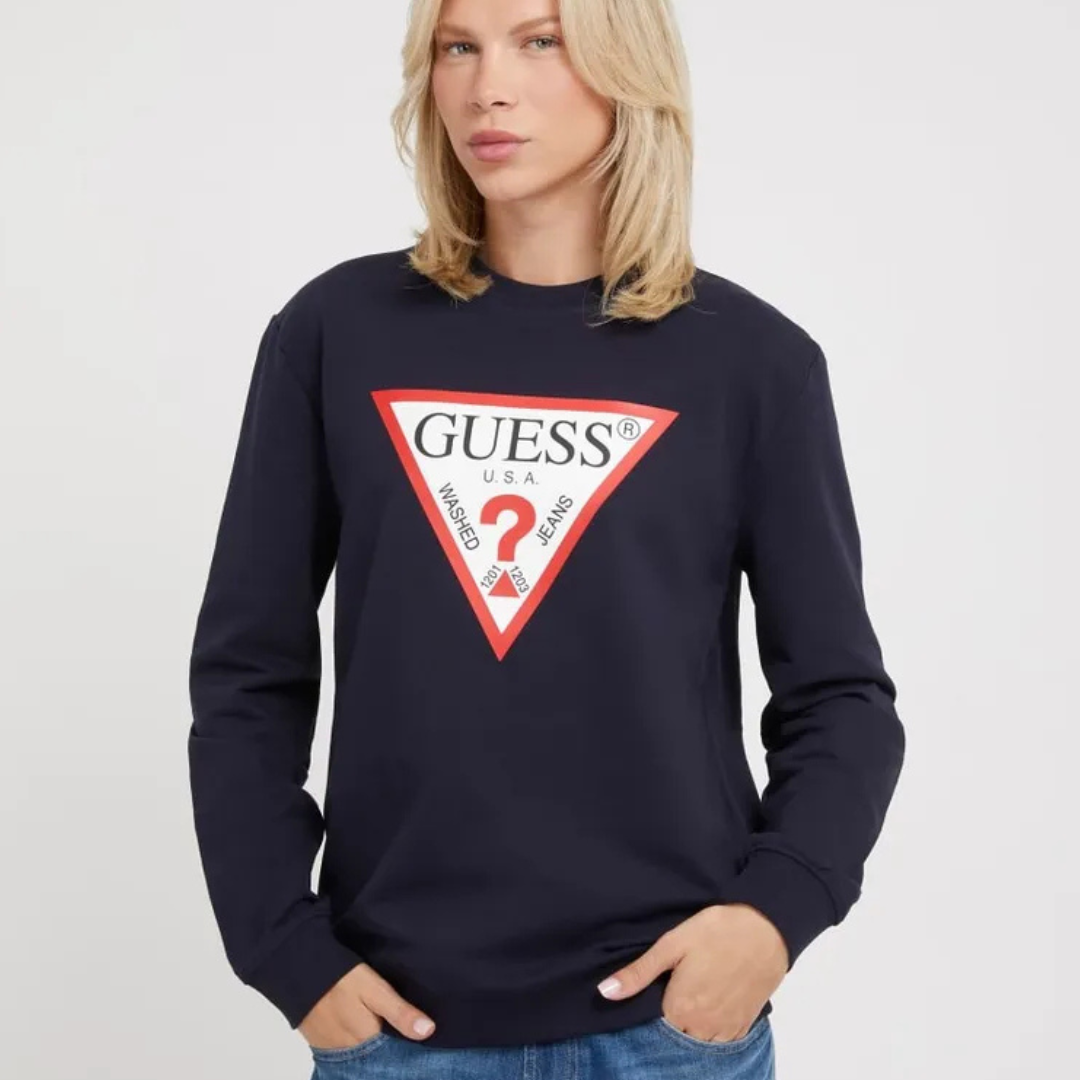 Mulher a usar sweatshirt preta da marca GUESS com logótipo triangular e jeans azuis