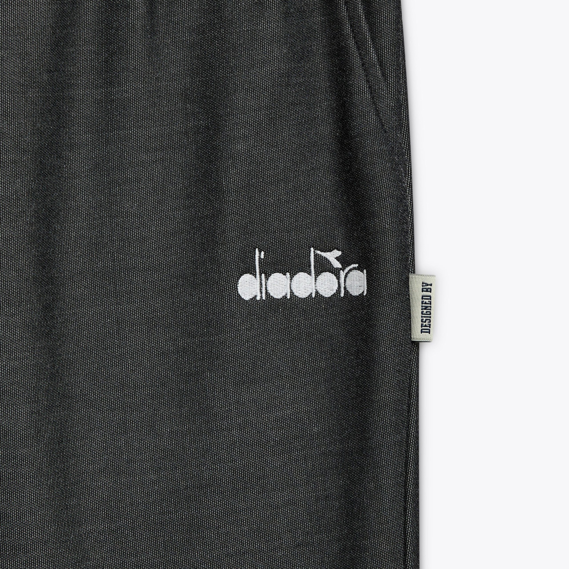 Calças pretas com logótipo diadora e etiqueta lateral