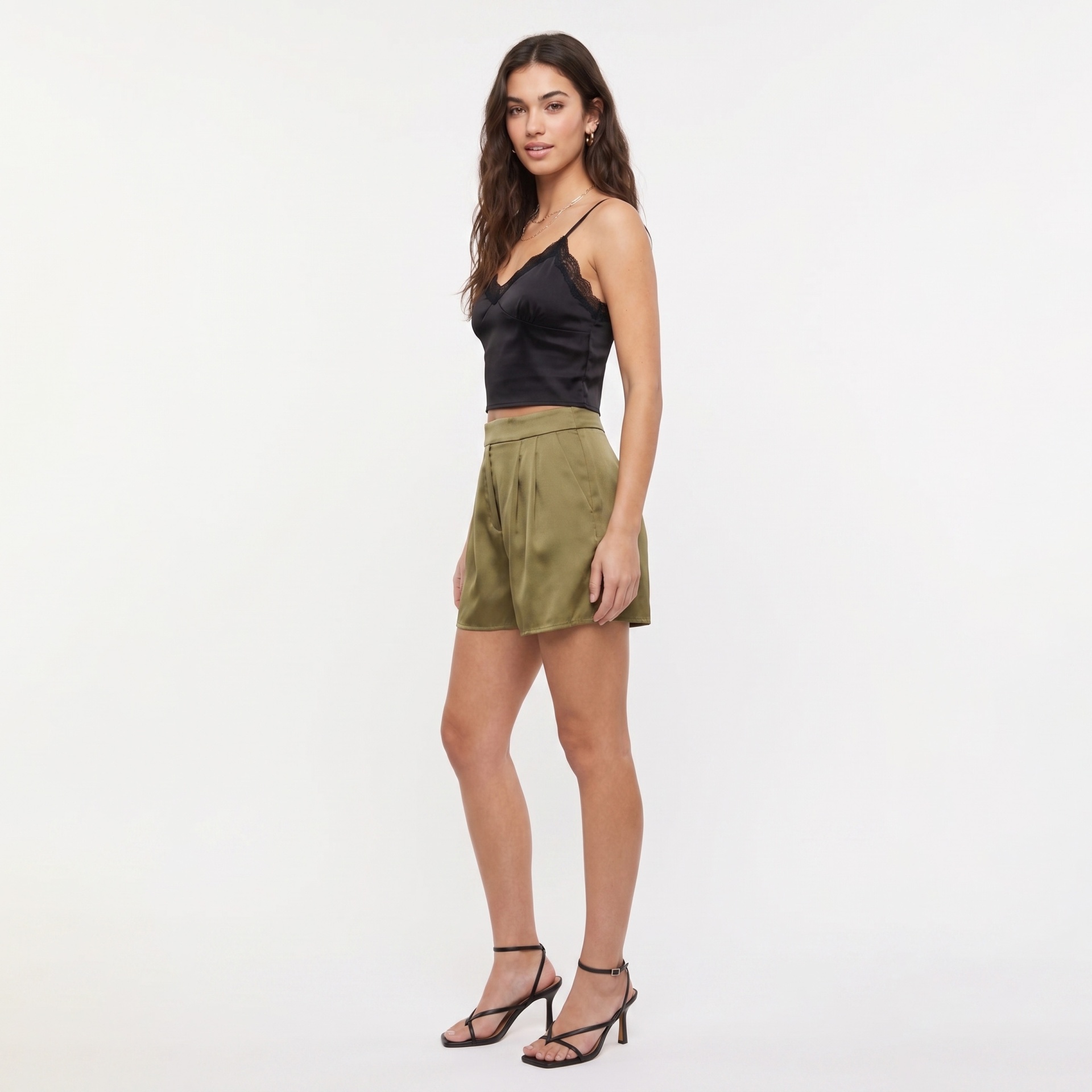 Mulher com top preto acetinado e calções verdes em fundo branco